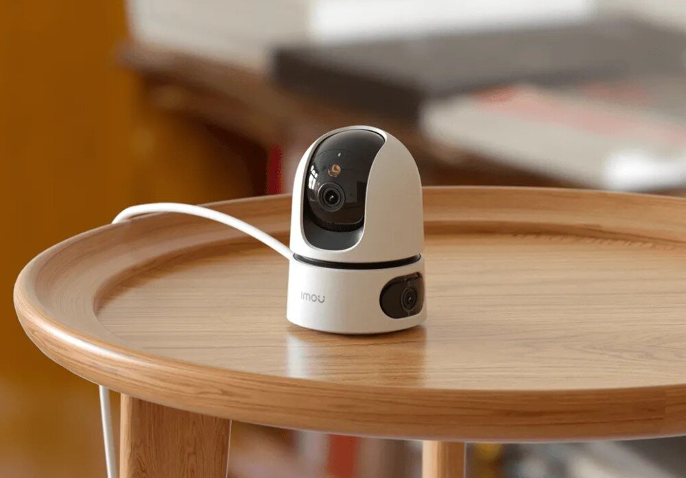 Biało-czarna kamera bezpieczeństwa na drewnianym stole, rozmyte tło.