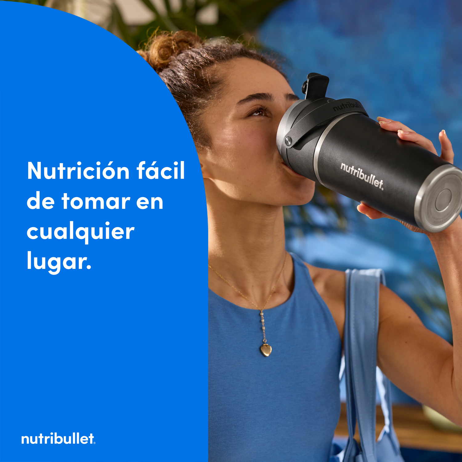 Mujer bebe de un agitador negro Nutribullet. Fondo azul con texto: Nutrición fácil en cualquier lugar.