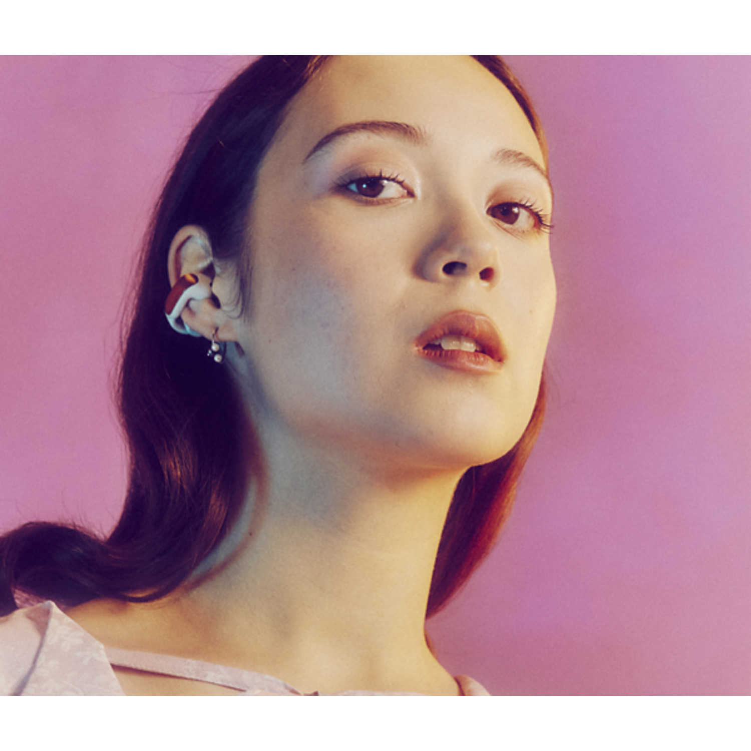 Woman with unique earring and a pink background.