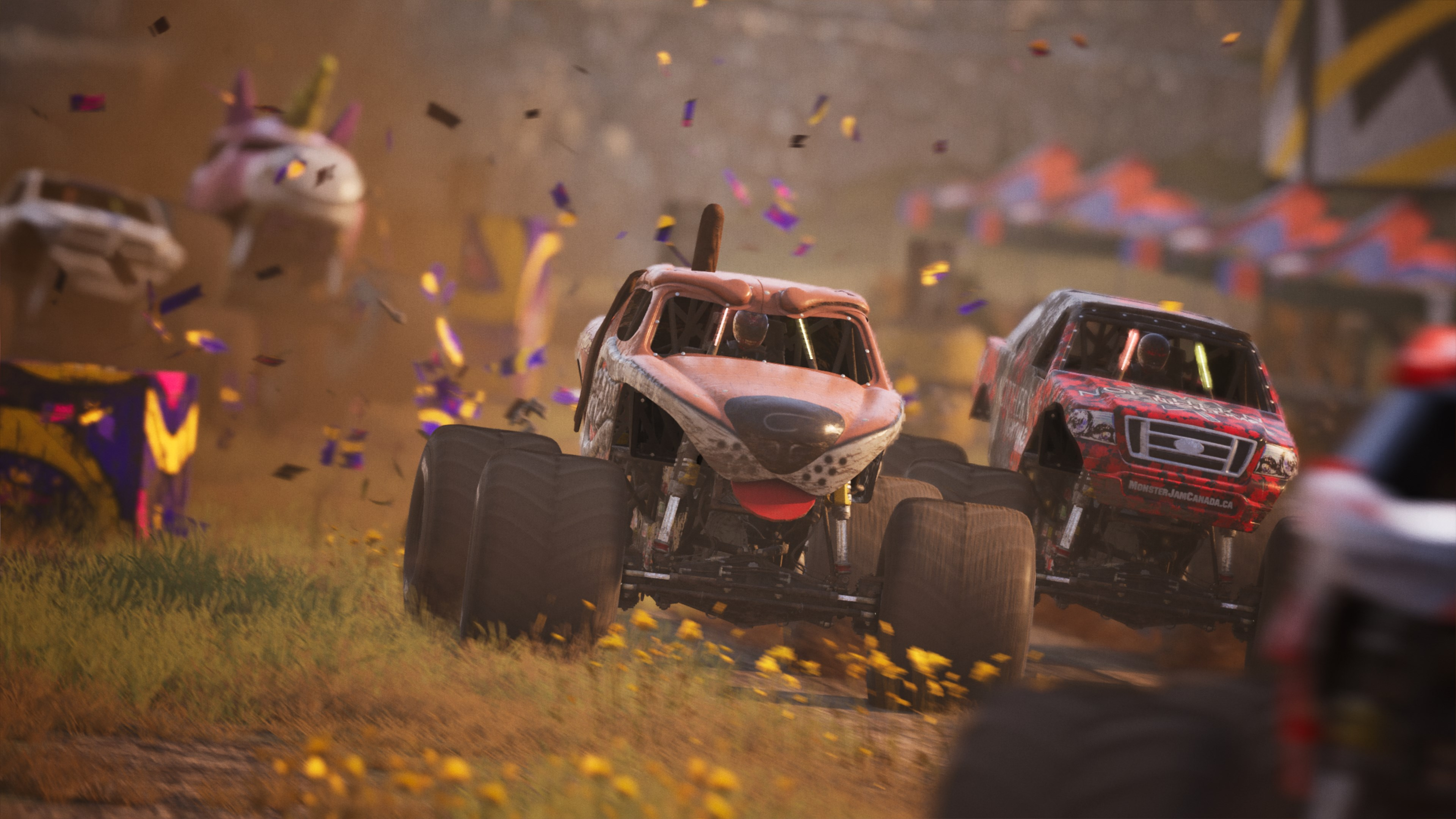 Monster truck che corrono su una pista sterrata, con una folla sfocata sullo sfondo.