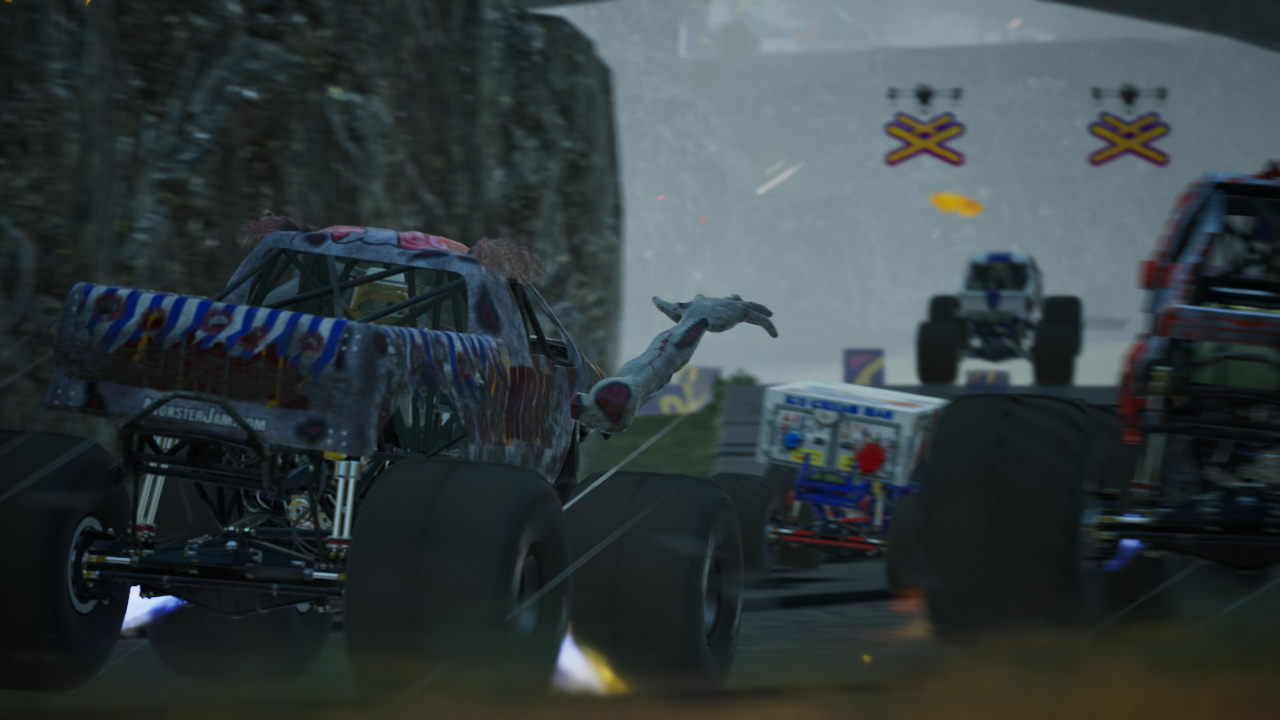 Gara di Monster truck. Un camion ha un tema zombie e un braccio zombie. Altri camion sullo sfondo.