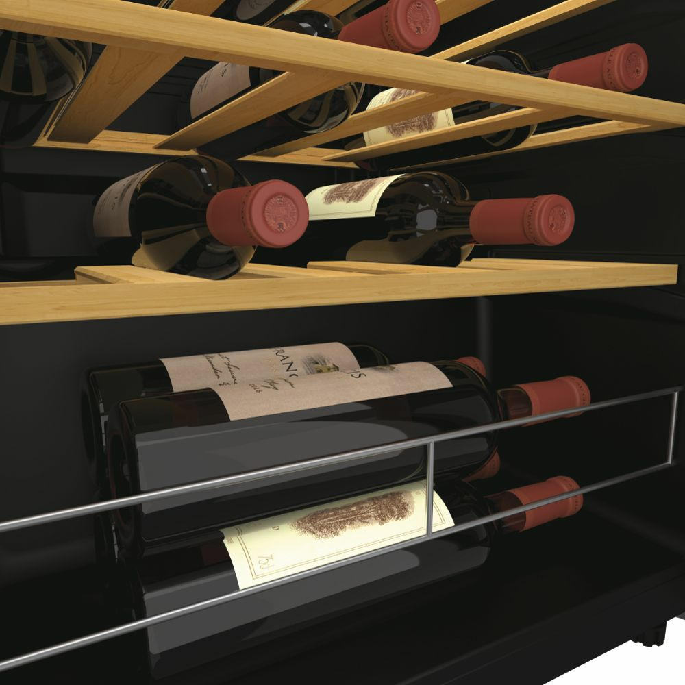 Interior de la vinoteca con estantes que sostienen botellas de vino. Las botellas son oscuras con tapas rojas, estantes de madera, interior negro.