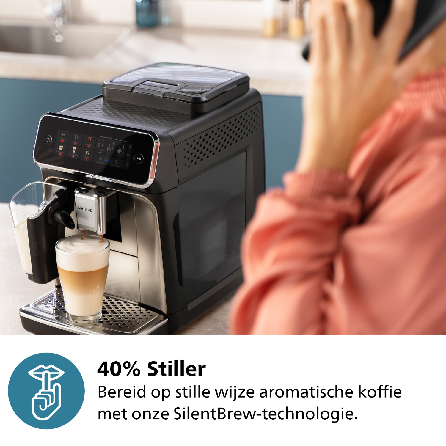Een persoon die een zwarte koffiemachine gebruikt, een kopje latte op de lekbak, een telefoon.