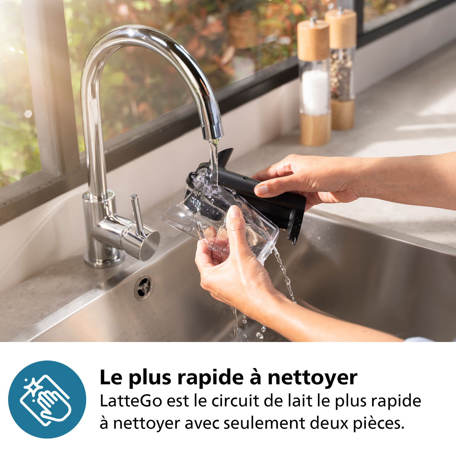 Mains lavant un système de lait LatteGo sous l'eau courante dans un évier de cuisine.