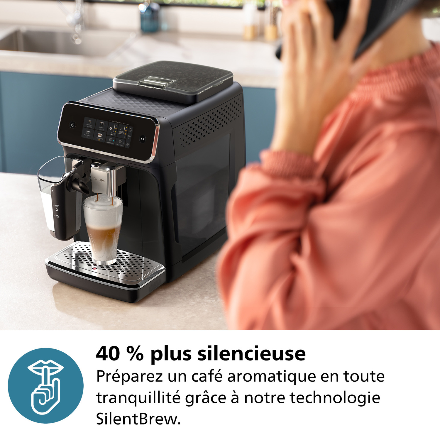 Machine à café préparant du café dans un verre, personne parlant au téléphone.