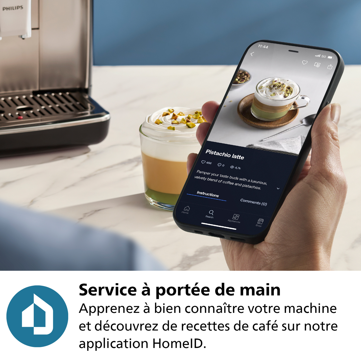 Une main tenant un smartphone avec une recette de café affichée. Une machine à café est à gauche.