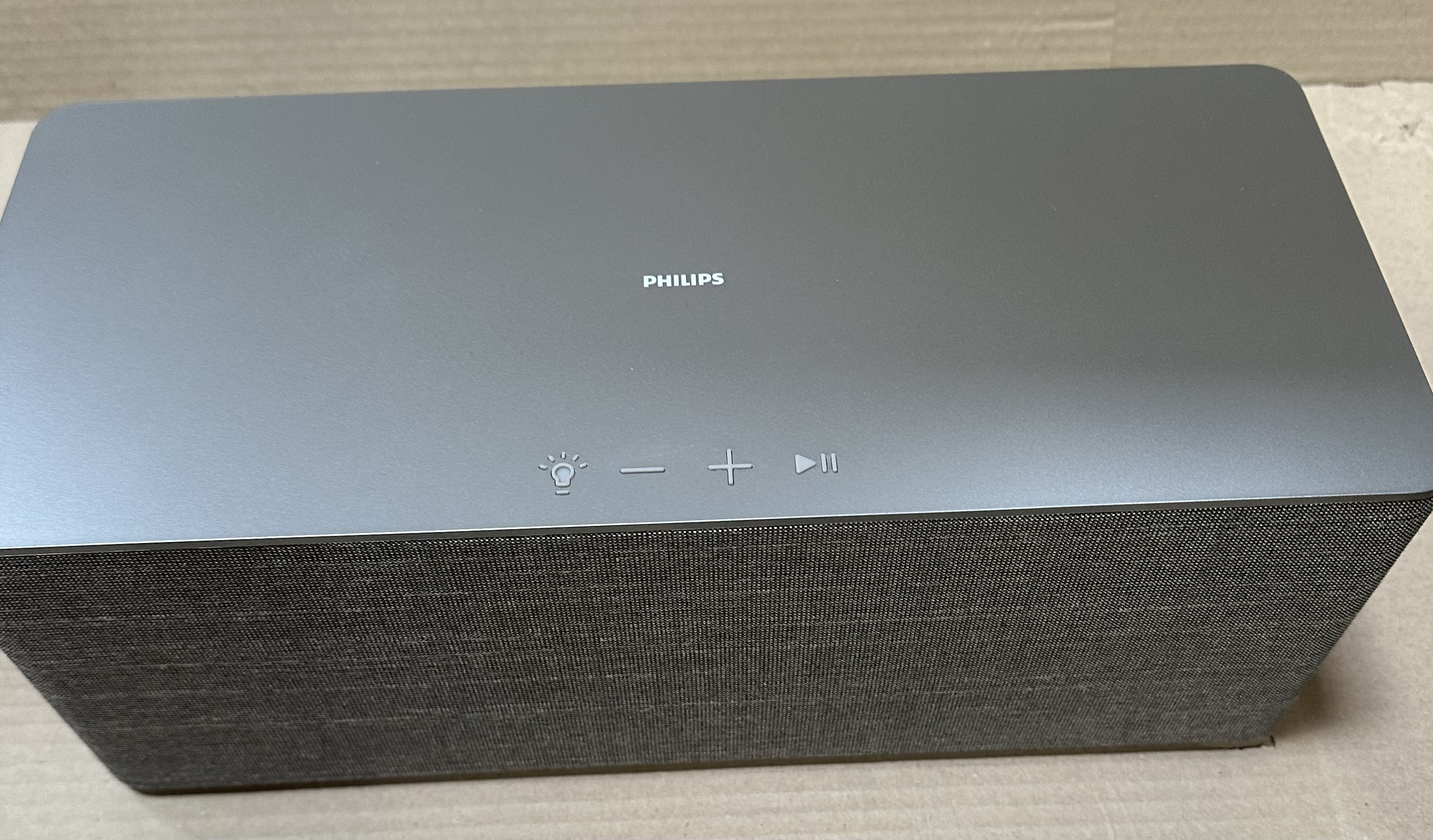 Ciemnoszary soundbar Philips umieszczony na białej powierzchni.