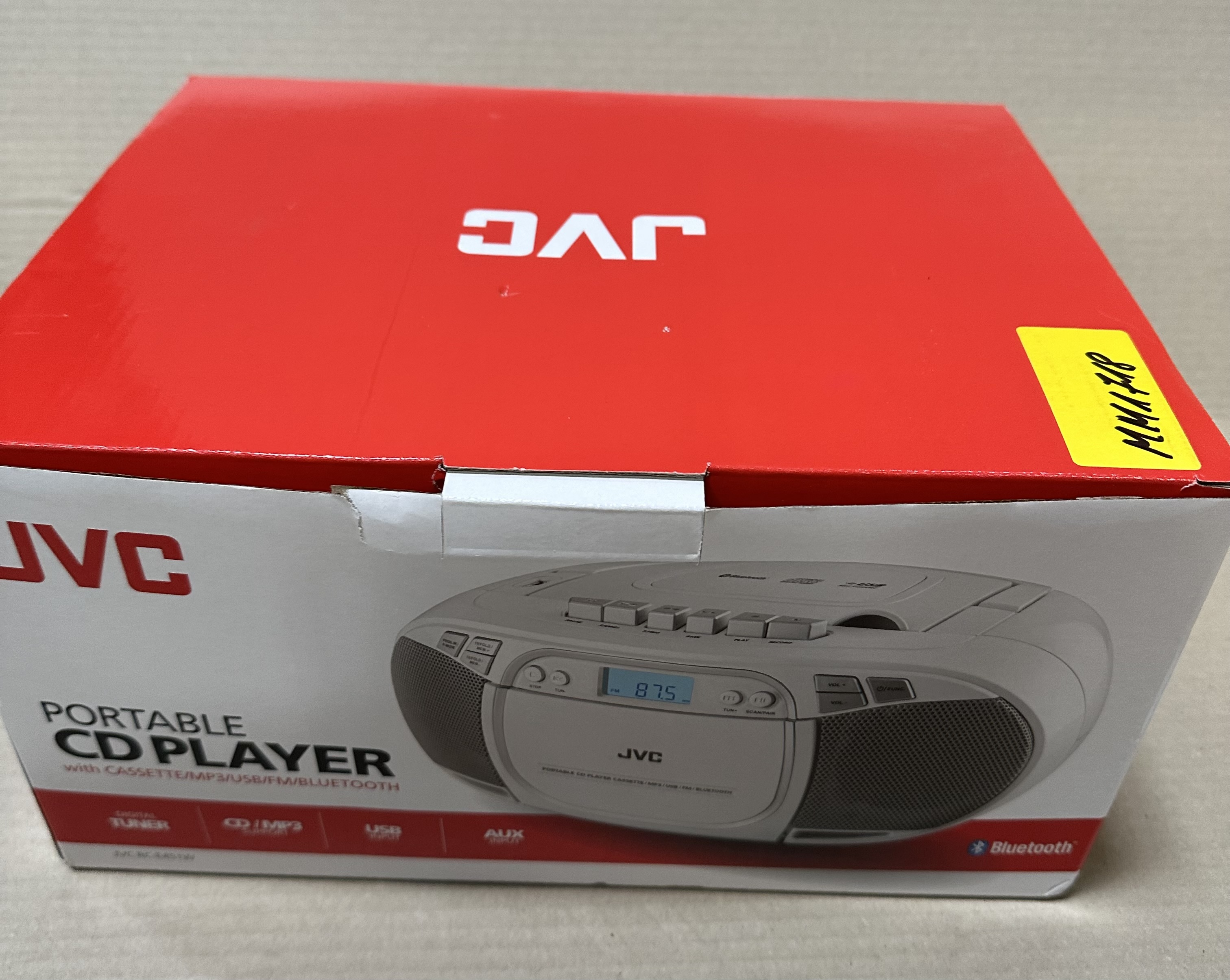 Pudełko przenośnego odtwarzacza CD JVC z odtwarzaczem kaset, MP3, USB i Bluetooth. Czerwono-białe pudełko.
