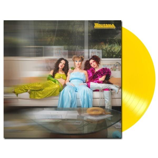Albumcover mit drei Frauen auf einem Sofa, einer gelben Schallplatte auf der rechten Seite und einem Glastisch.