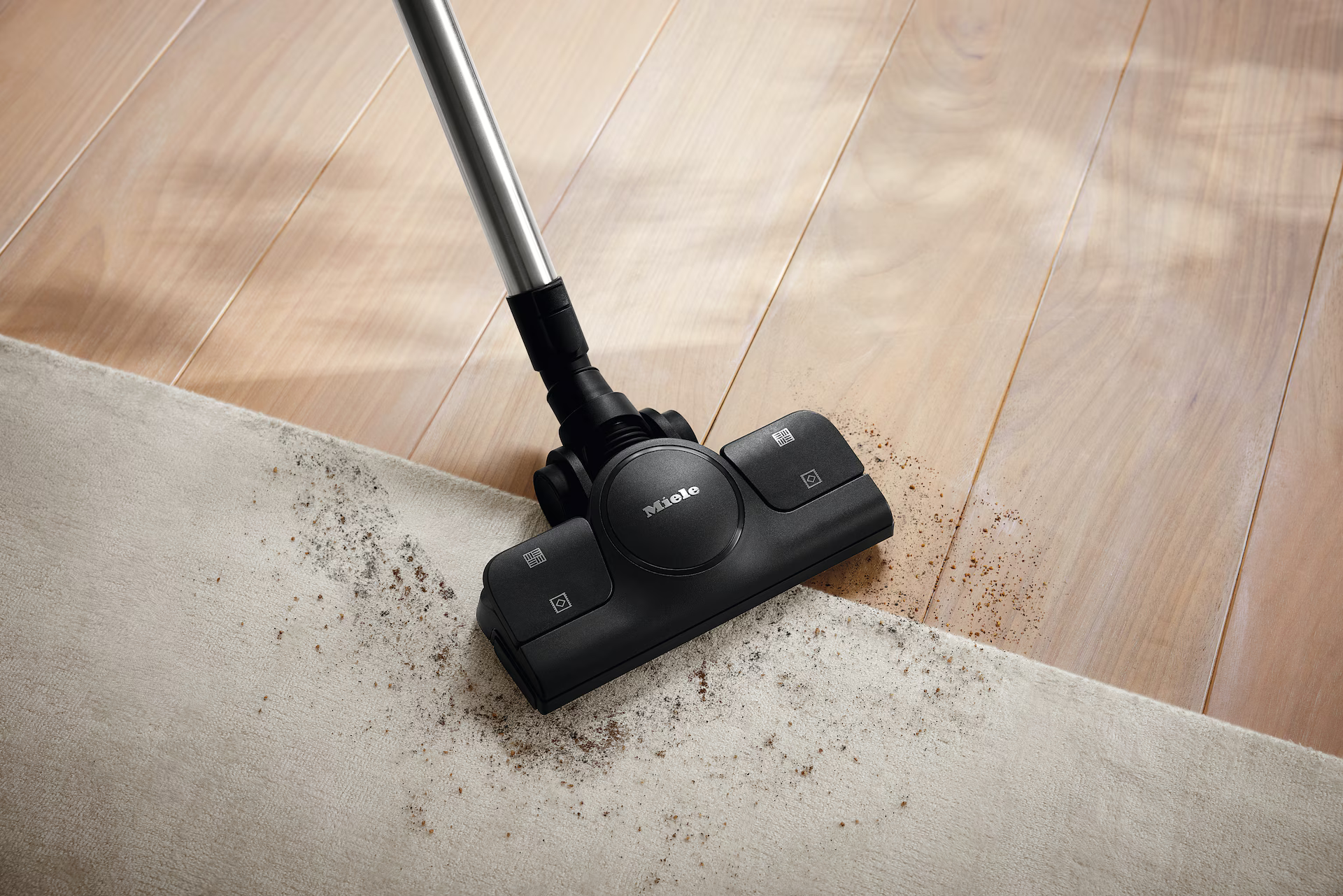 Ein Staubsauger auf einem Teppich. Der Teppich ist mit Schmutz bedeckt. Holzboden im Hintergrund.