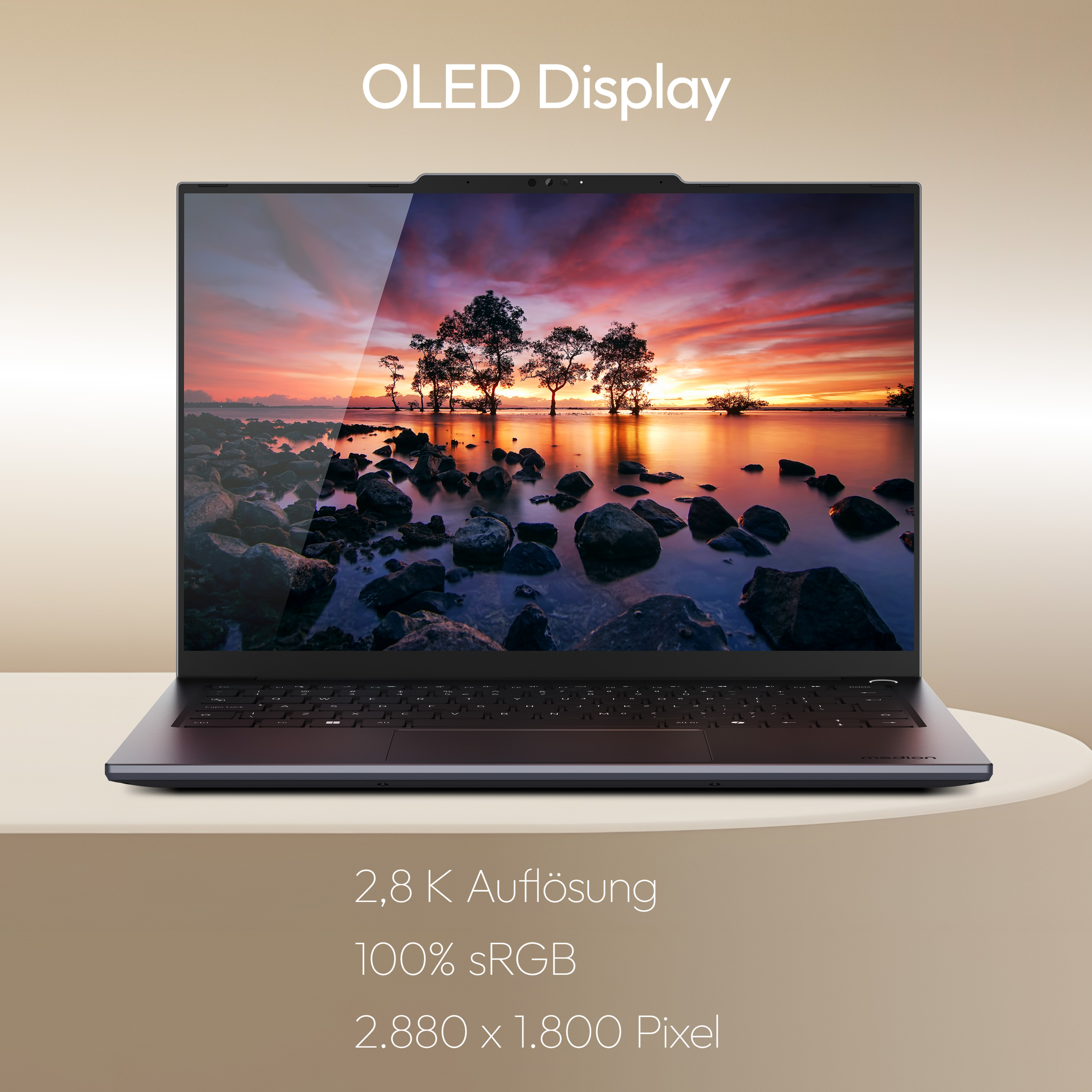 Laptop mit OLED-Display, das einen Sonnenuntergang über einer felsigen Küste zeigt.