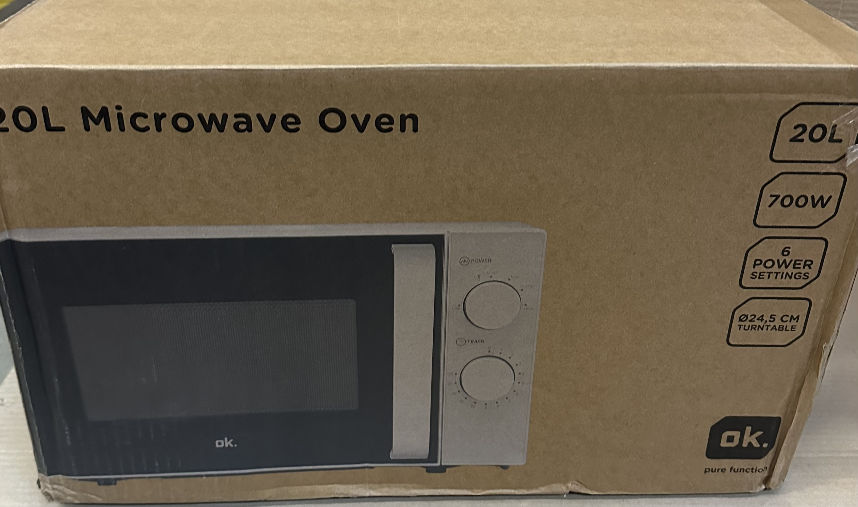 Pudełko po kuchence mikrofalowej, brązowe ze zdjęciem kuchenki i pokrętłami. Tekst opisuje funkcje.