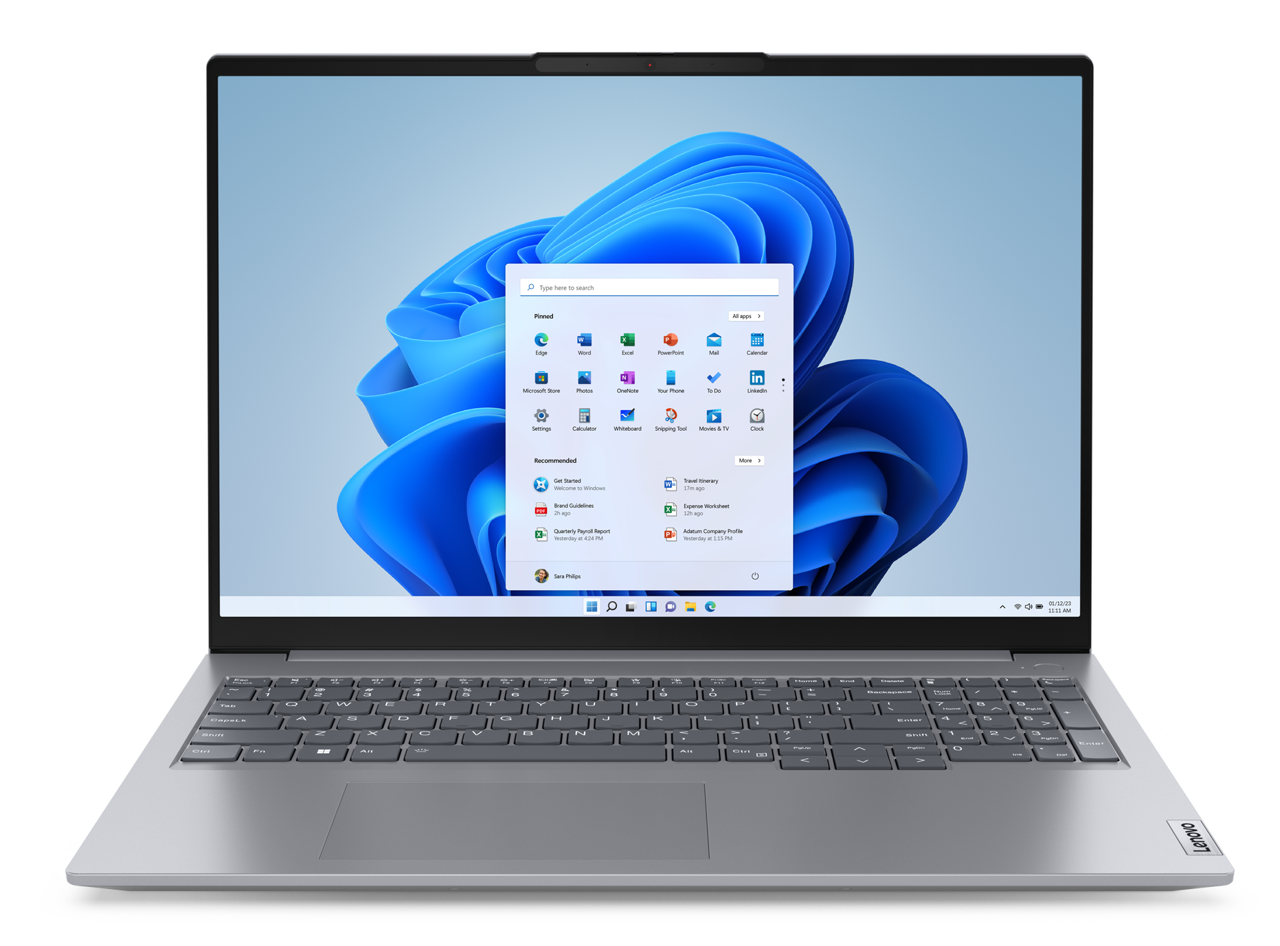 Srebrny laptop, otwarty, wyświetla Windows 11 z ikonami aplikacji. Otwarte jest białe okno.