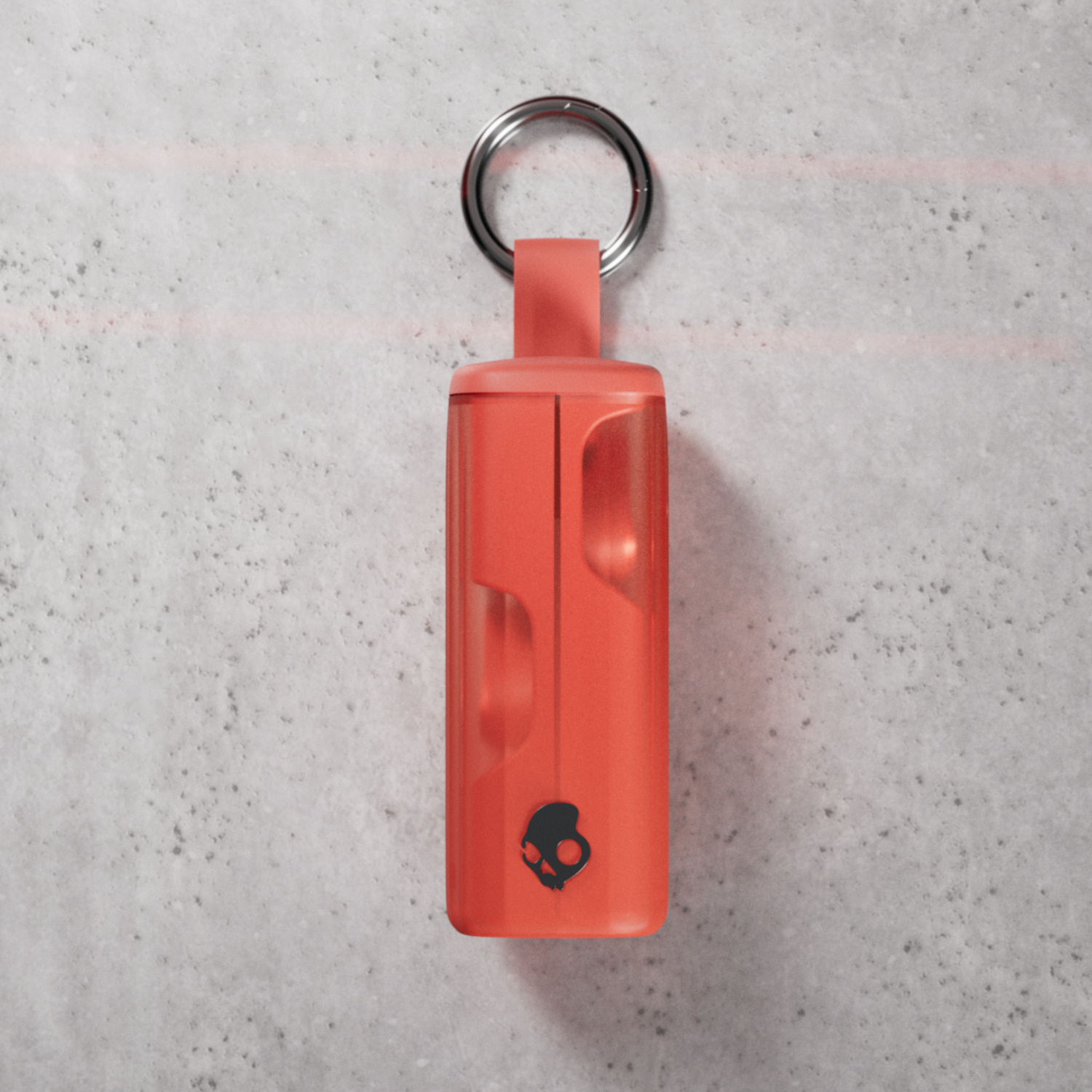 Roter Skullcandy-Schlüsselanhänger mit Metallring auf grauer Oberfläche.