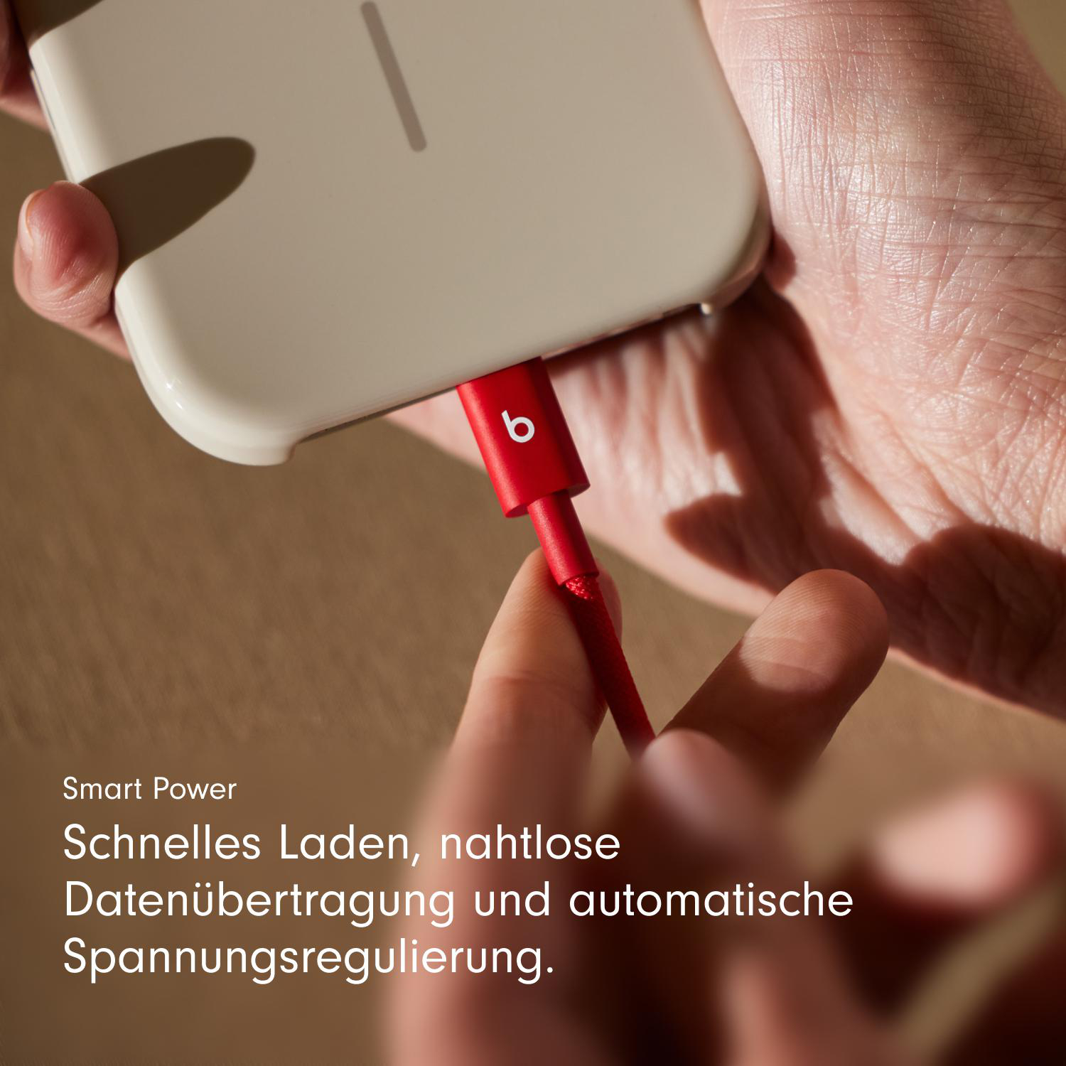 Ein rotes Ladekabel ist in ein weißes Telefon gesteckt. Das Kabel hat ein rotes 'b' Logo.