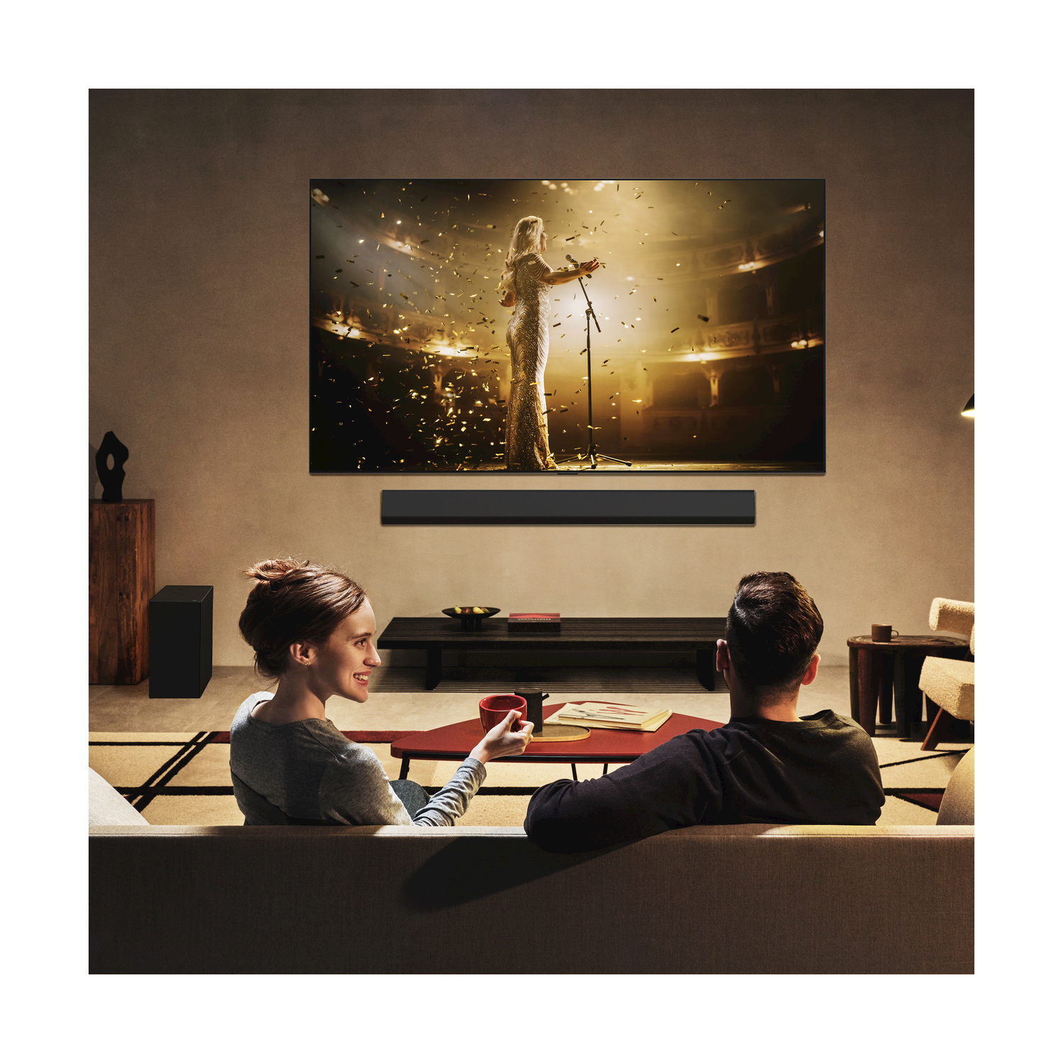 Coppia che guarda la TV con soundbar e subwoofer.