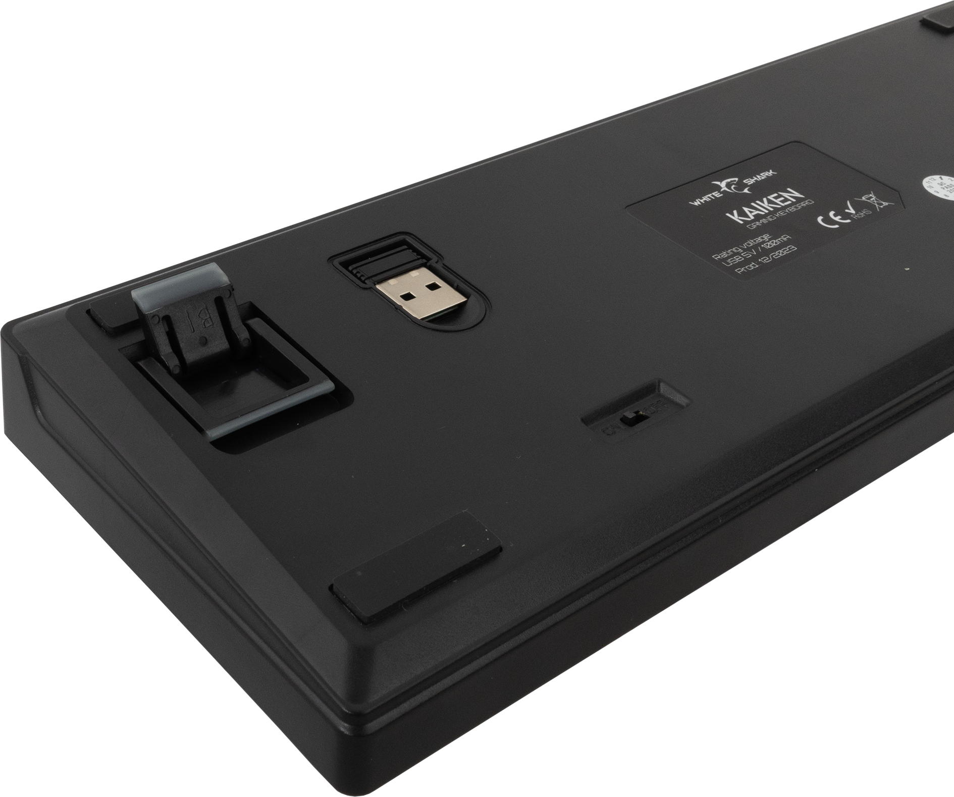 Egy fekete billentyűzet alja USB-csatlakozóval és támasztólábakkal.