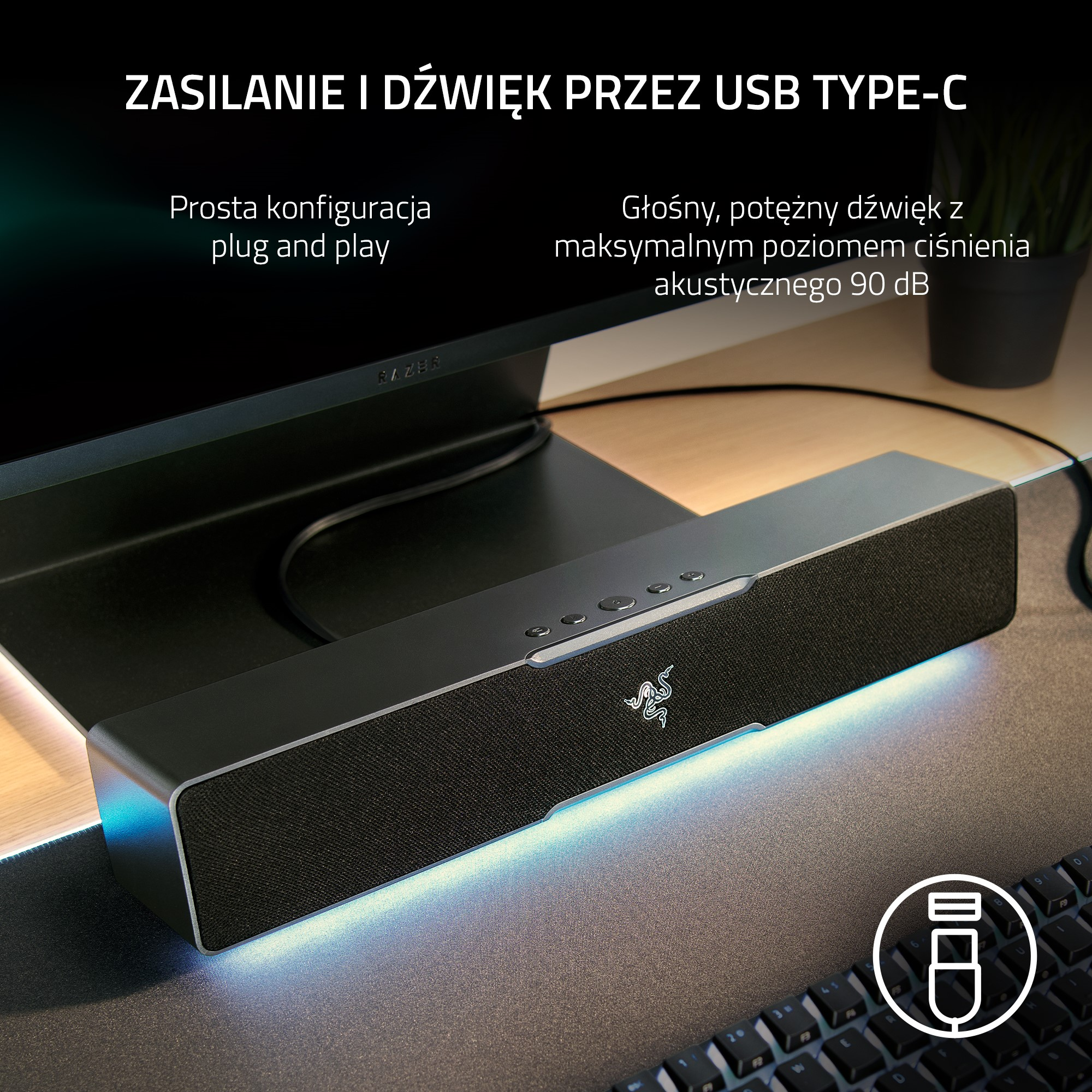 Konfiguracja soundbaru i klawiatury. Czarny soundbar na biurku. Klawiatura na biurku. Tekst na górze.
