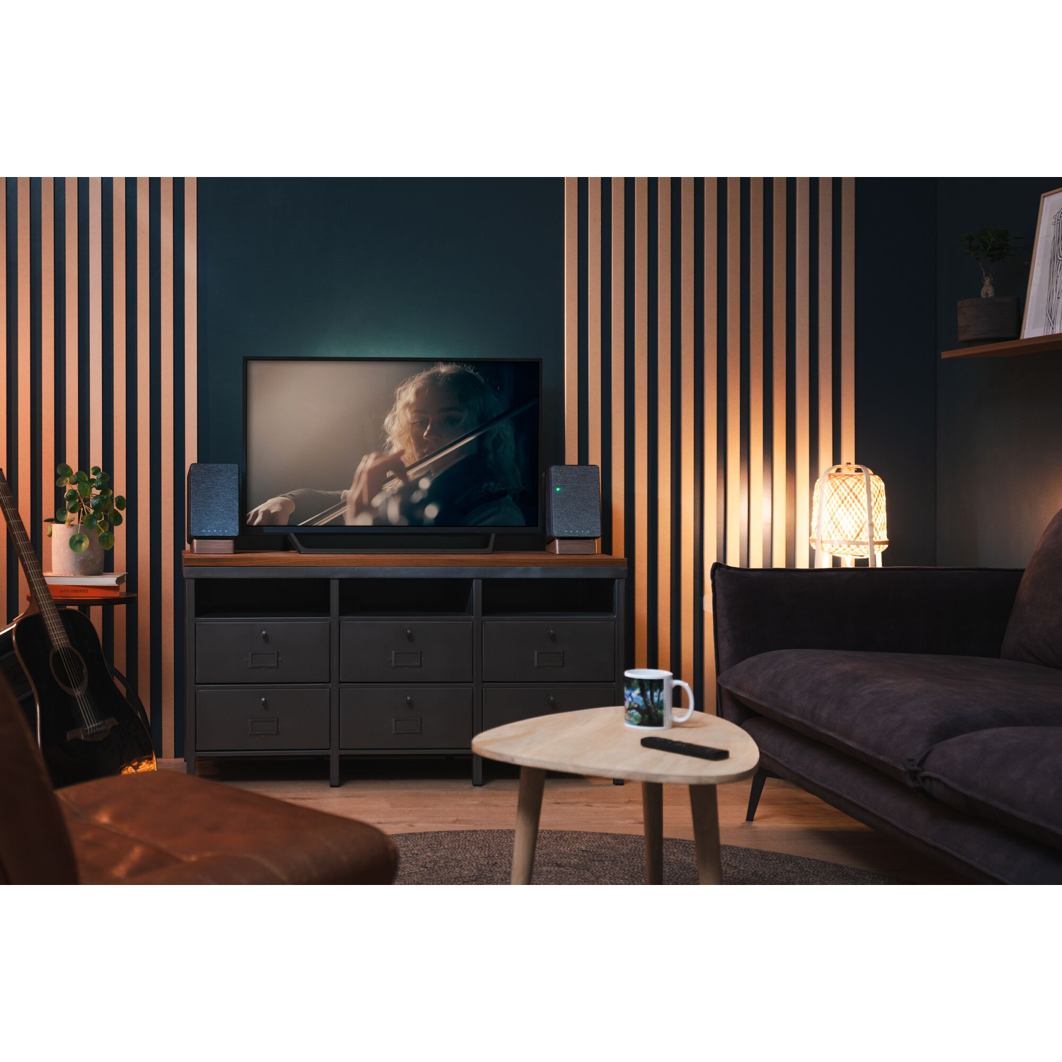 Woonkamer met tv, speakers, gitaar, bank en salontafel.