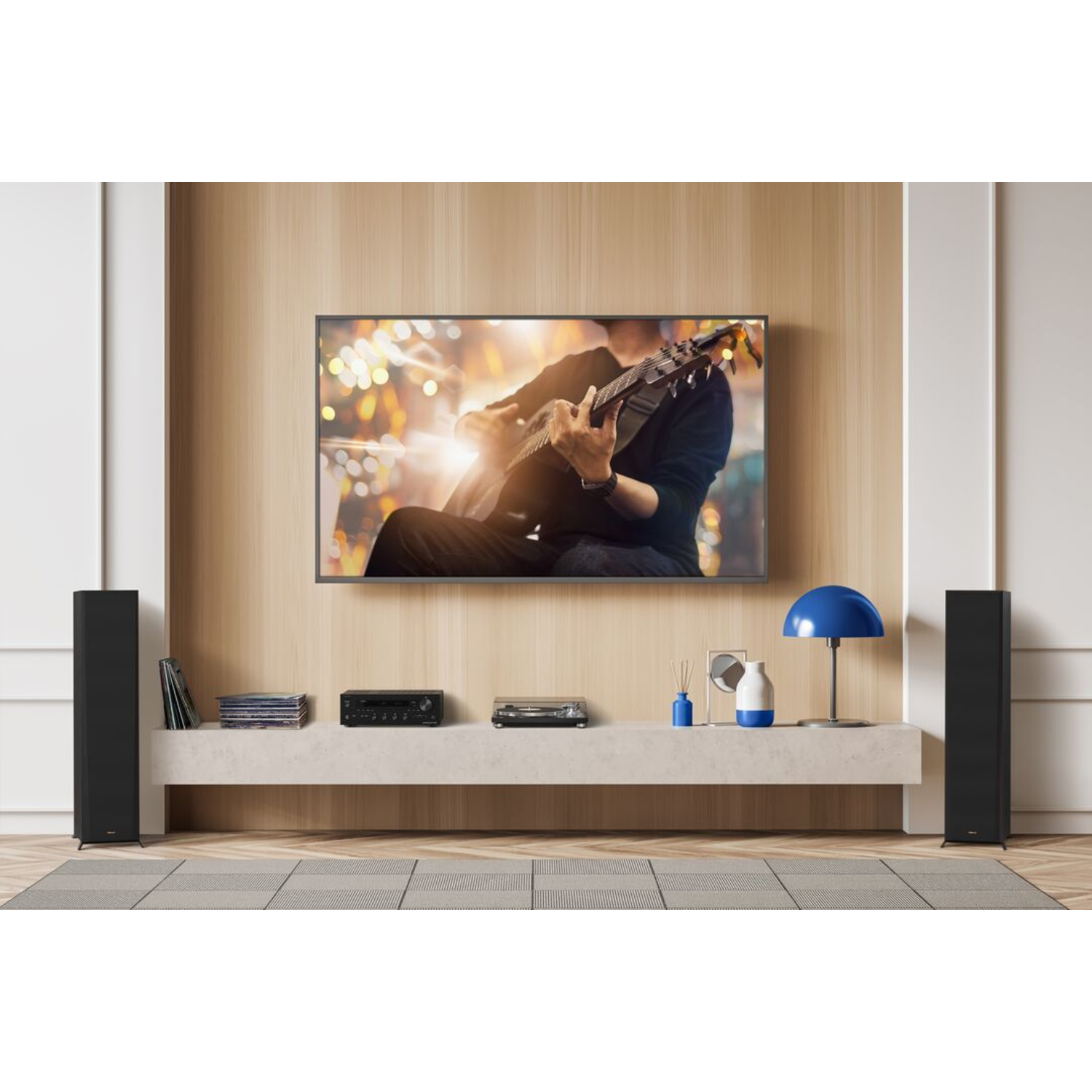 A living room with a large TV, speakers, and a person playing guitar on screen.