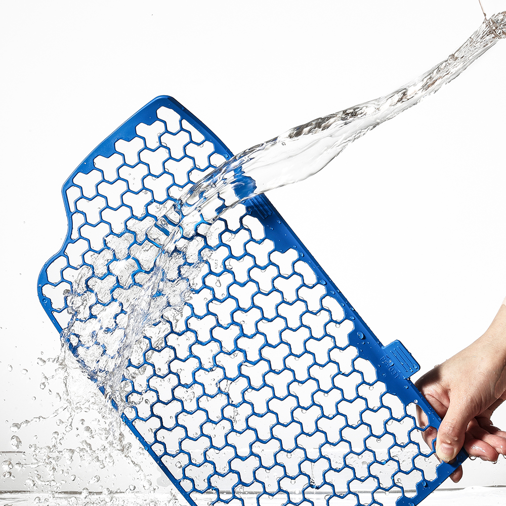 Un tappetino blu a motivo a nido d'ape viene lavato con acqua.