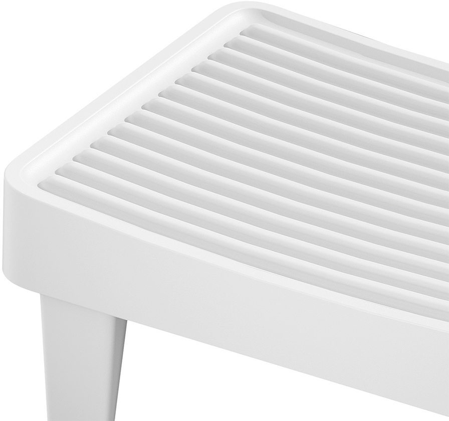 Primo piano di uno sgabello o gradino bianco e scanalato. La superficie presenta scanalature parallele.