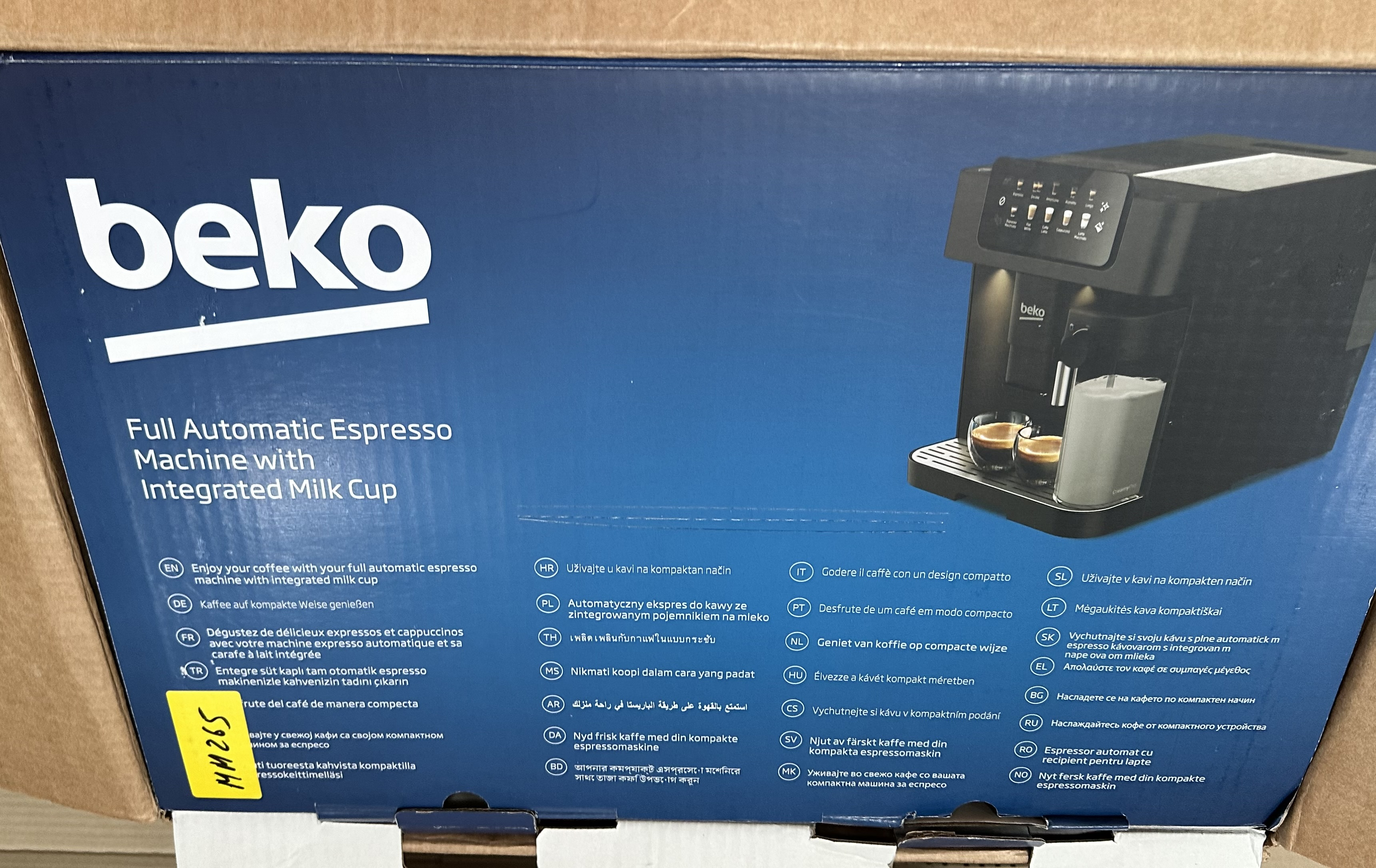 Ekspres do kawy z zintegrowanym pojemnikiem na mleko. Pudełko zawiera tekst w wielu językach.