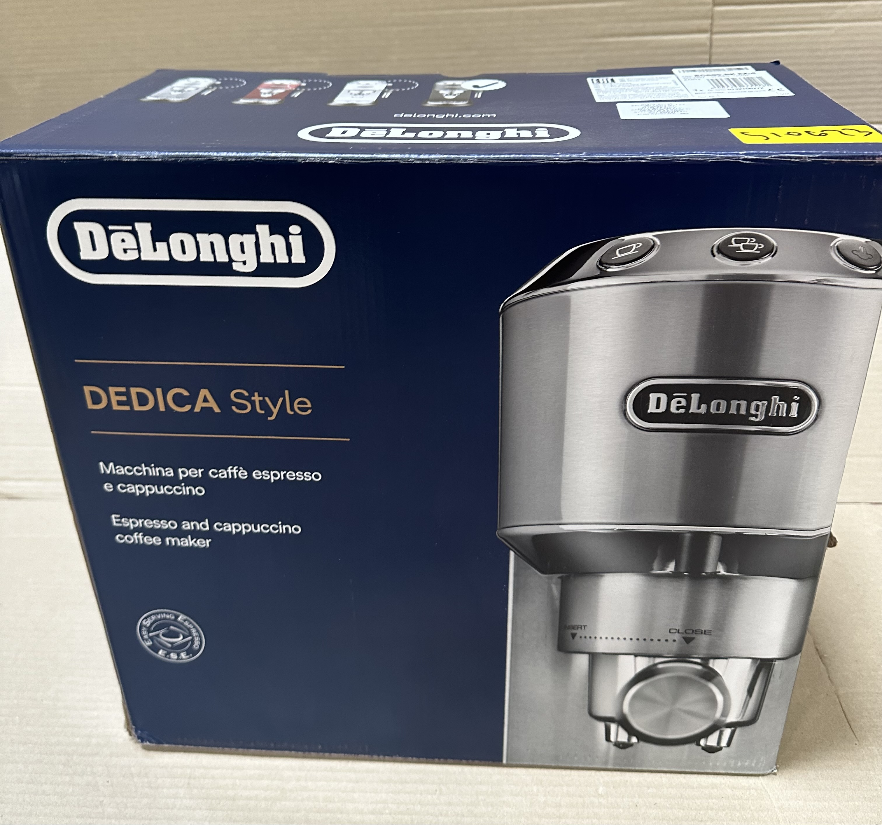 Pudełko ekspresu do kawy Delonghi Dedica Style, z maszyną widoczną po prawej stronie.