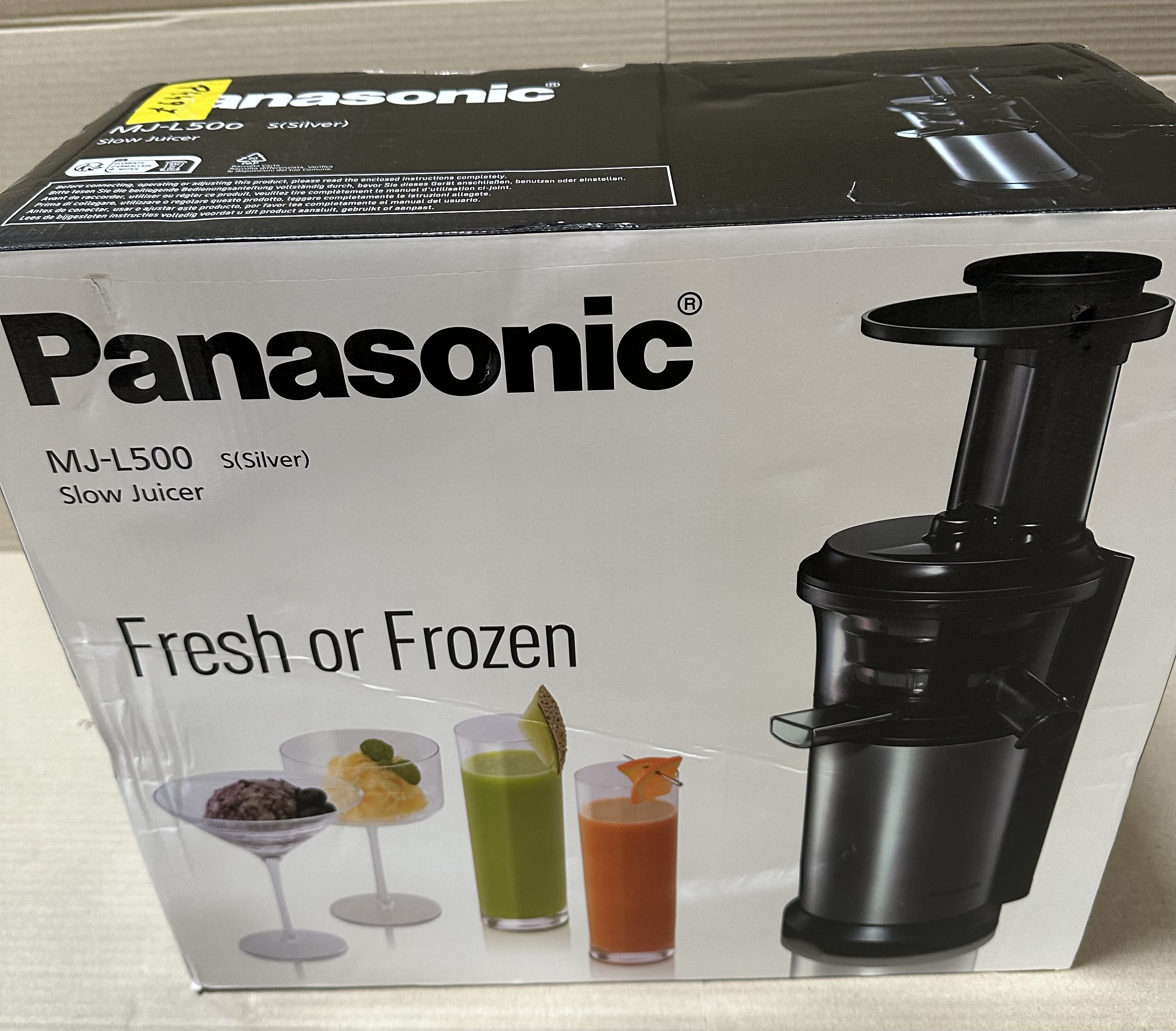 Pudełko do wyciskarki Panasonic z wyciskarką i trzema szklankami soku przed nią.
