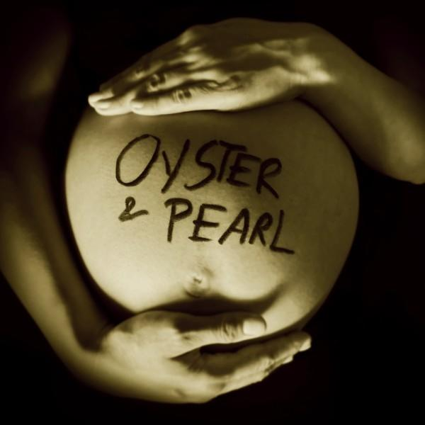 Schwangerer Bauch mit den Worten "Oyster & Pearl" darauf geschrieben, gehalten von Händen, Sepia-Ton.