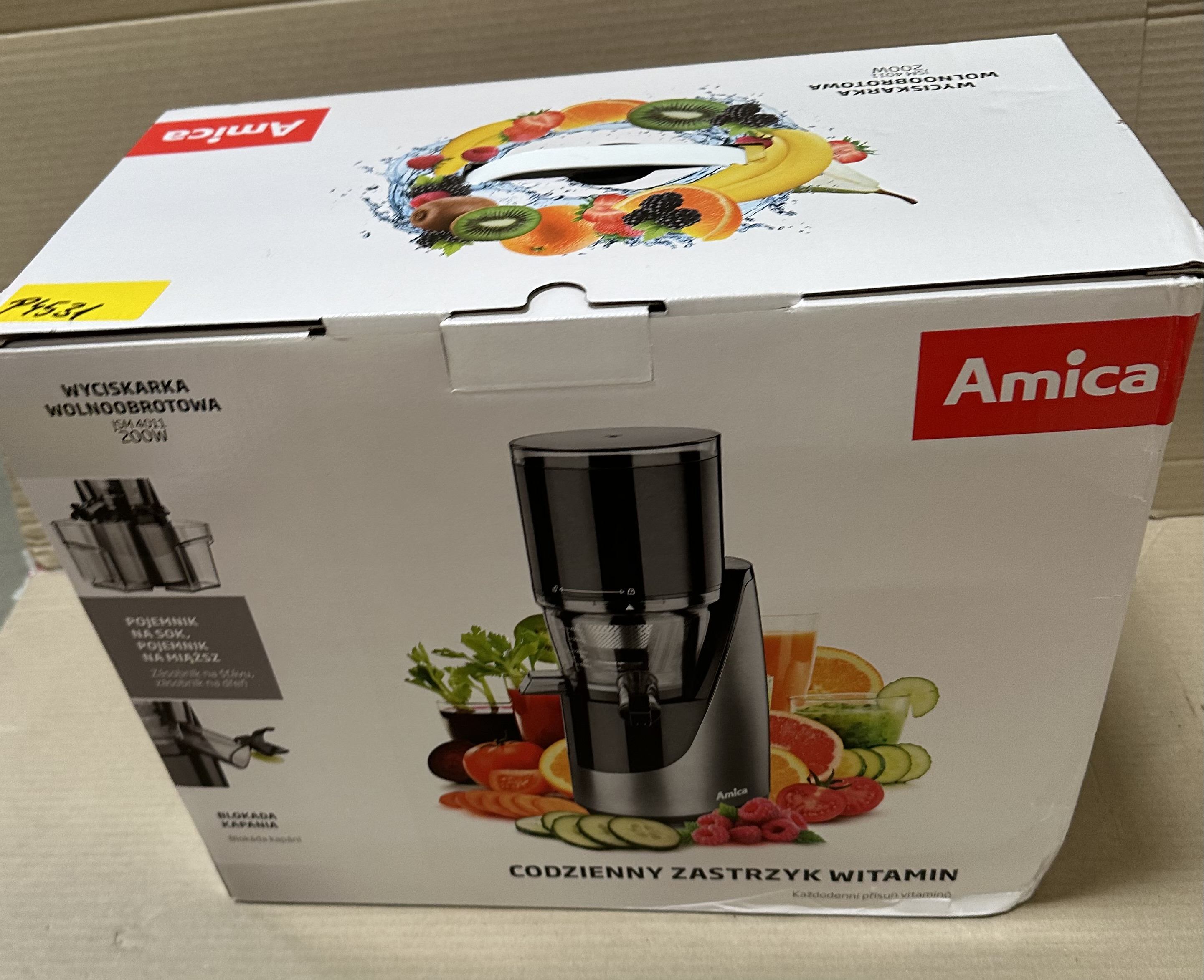 Pudełko do wyciskarki. Pokazuje wyciskarkę i owoce. Marka to Amica.