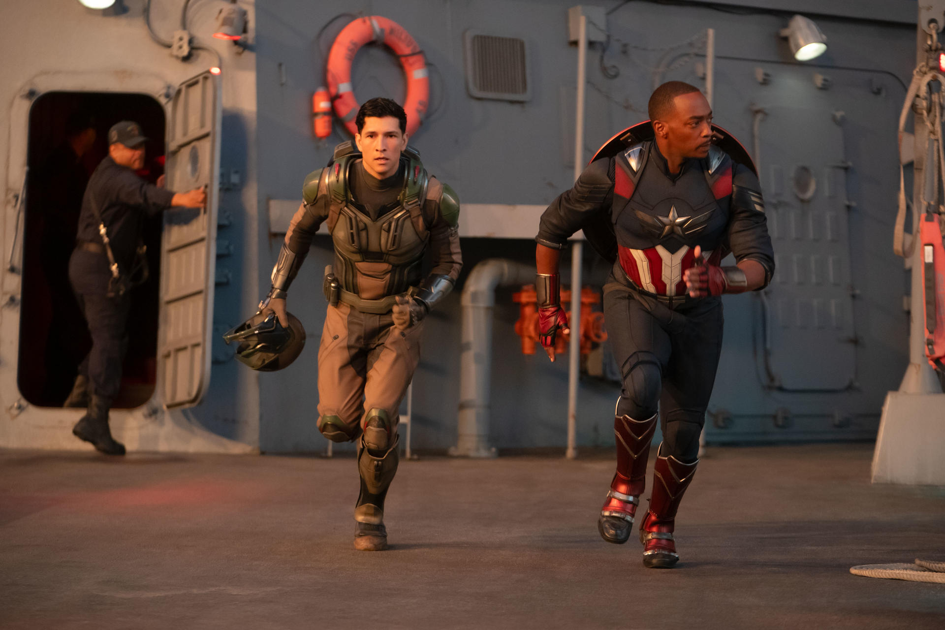 Zwei Männer rennen auf einem Schiffsdeck. Einer im Captain America-Outfit, der andere in einem futuristischen Anzug.
