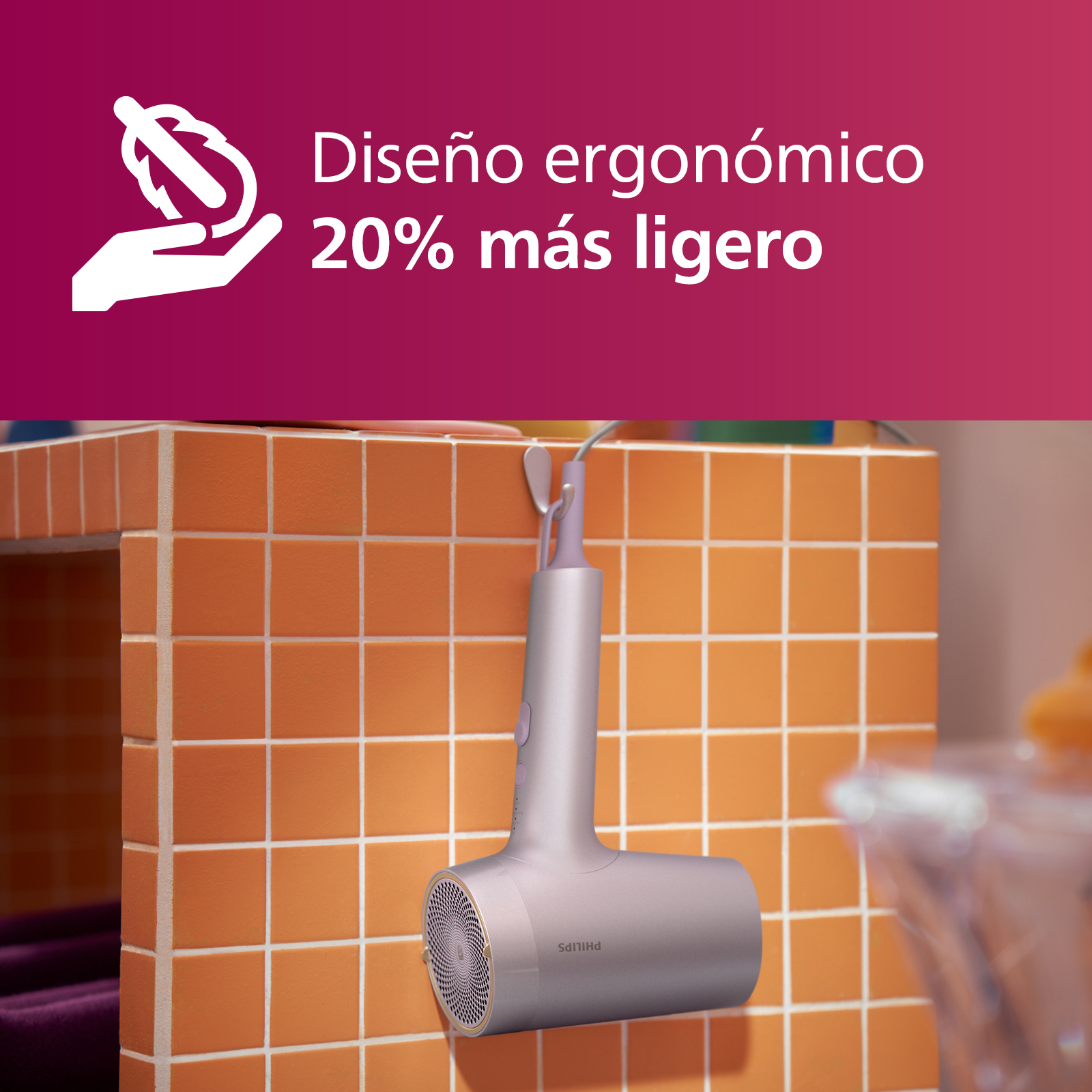 Secador de pelo rosa y morado colgando de un gancho con azulejos naranjas.