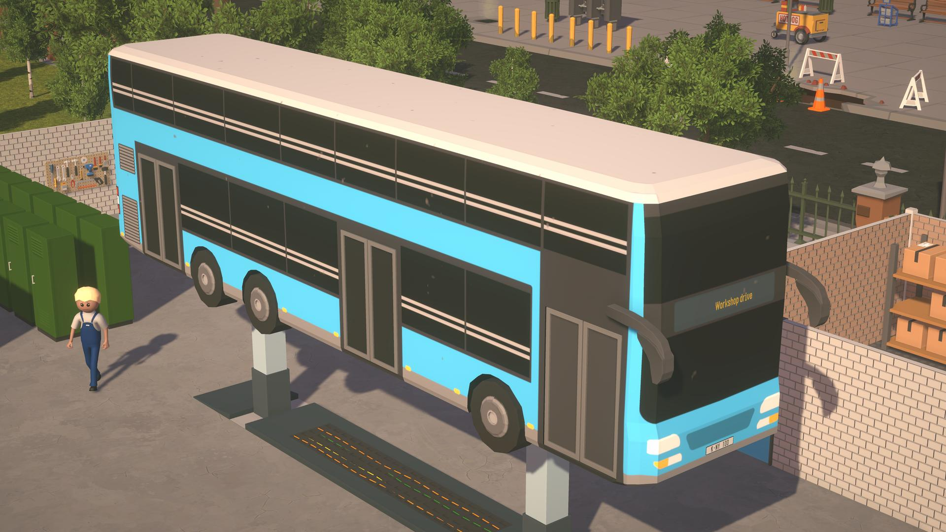 Blauer Doppeldeckerbus auf einer Hebebühne. Ein Arbeiter steht daneben. Bauarbeiten und andere Fahrzeuge im Hintergrund sichtbar.