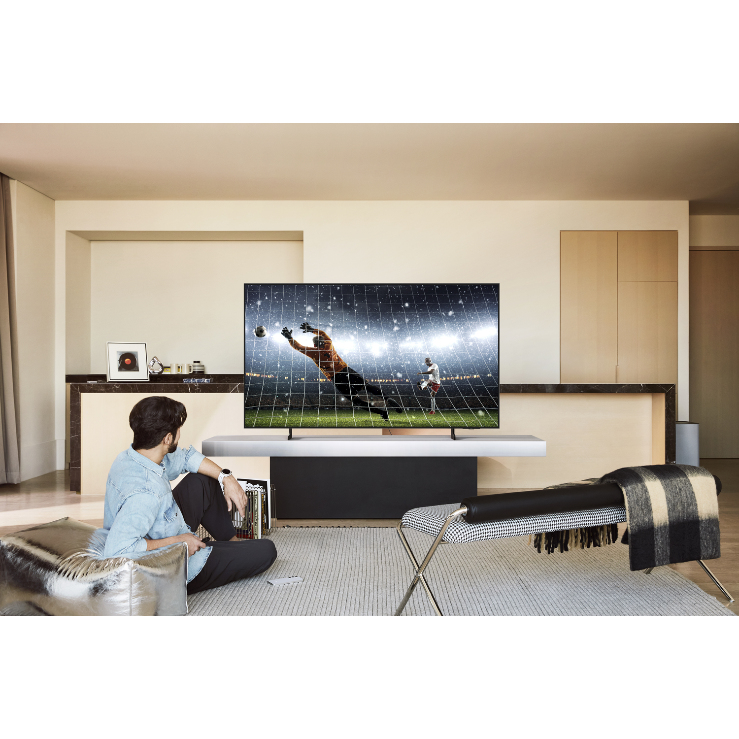 Man bekijkt voetbal op tv in een moderne woonkamer.