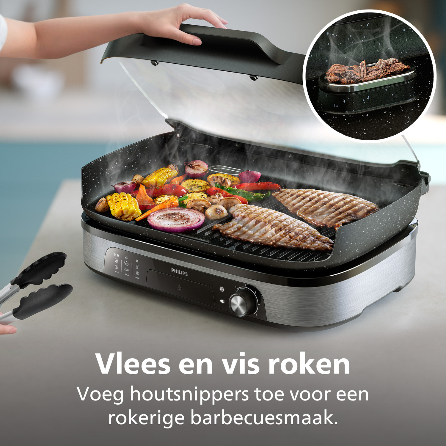 Electric grill with vegetables and fish. Hand lifting the lid. Tongs are in the foreground. Text: Smoke meat and fish.