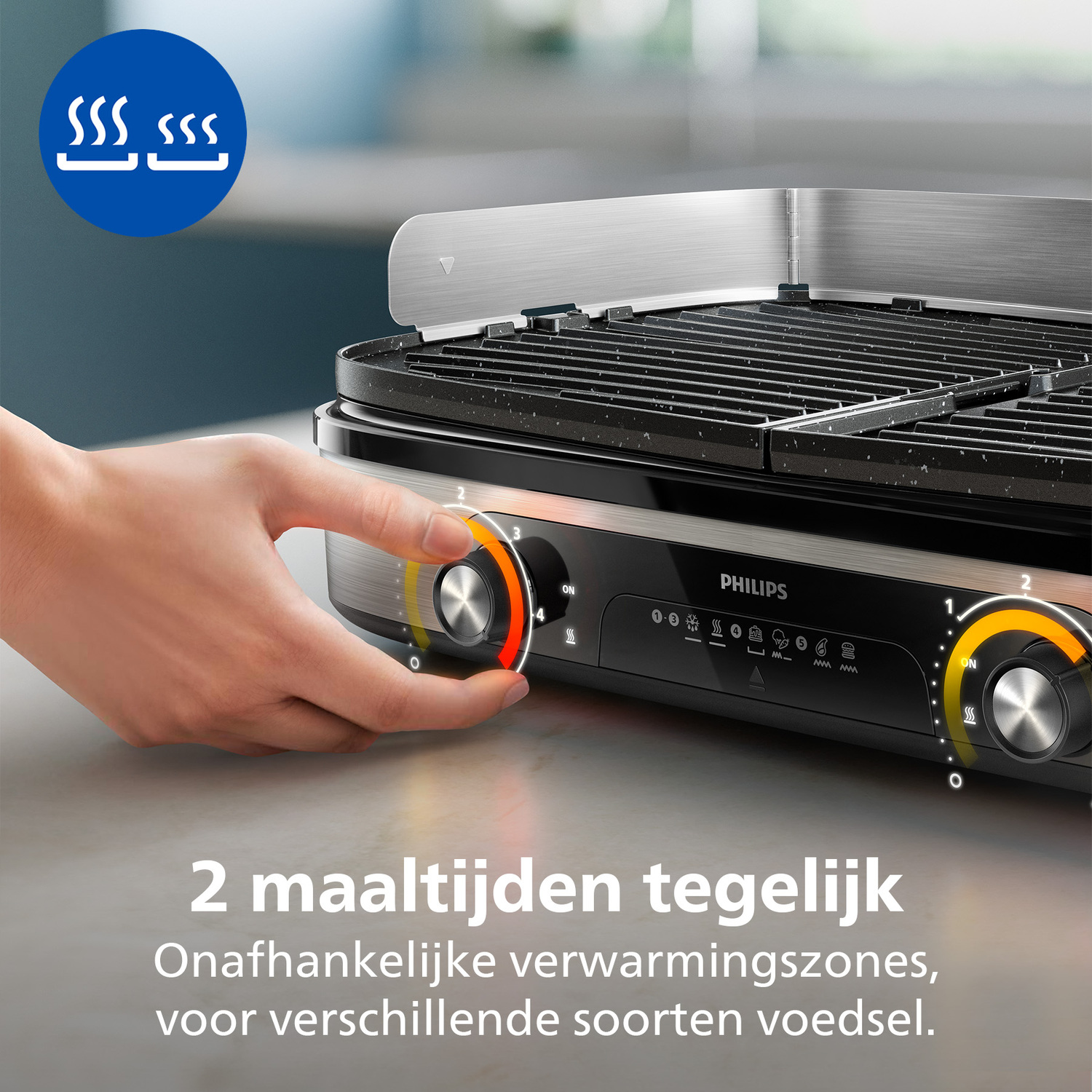 A hand turns a dial on a Philips grill. The grill is black with silver accents. Text reads: 2 meals at once, independent heating zones.