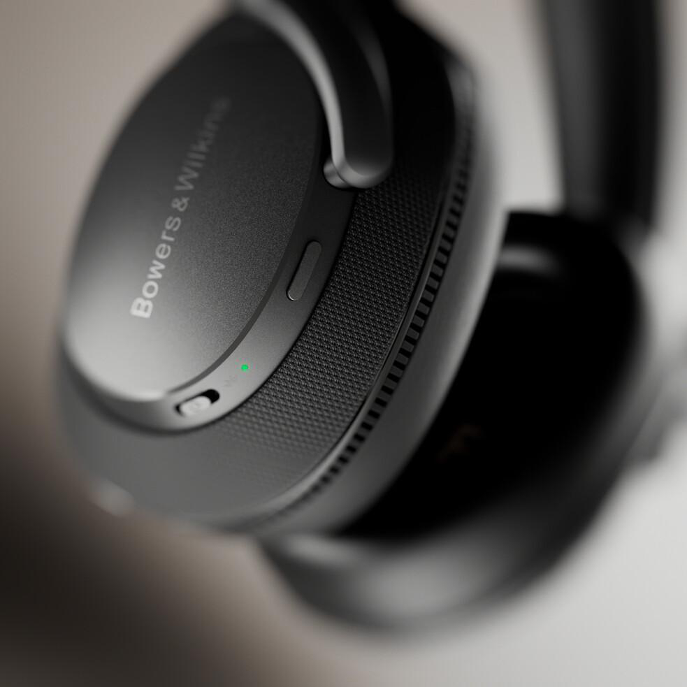 Schwarze Kopfhörer, Marke Bowers & Wilkins, schräge Ansicht, Fokus auf den Ohrmuschel.