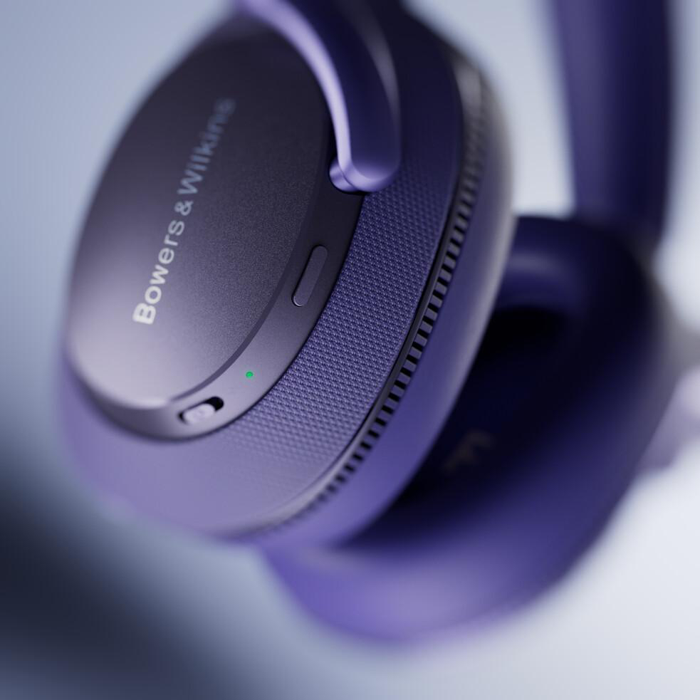 Nahaufnahme von lila Bowers & Wilkins Kopfhörern, die den Markennamen und Design-Details zeigen.