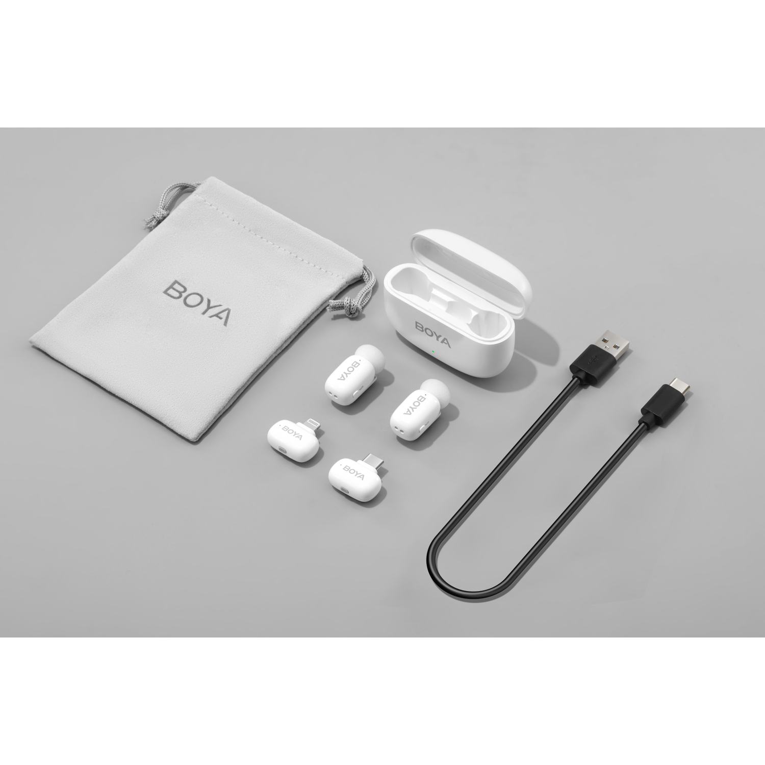 BOYA audio-apparatuurset op een grijs oppervlak, inclusief een hoesje, oortelefoons en een kabel.