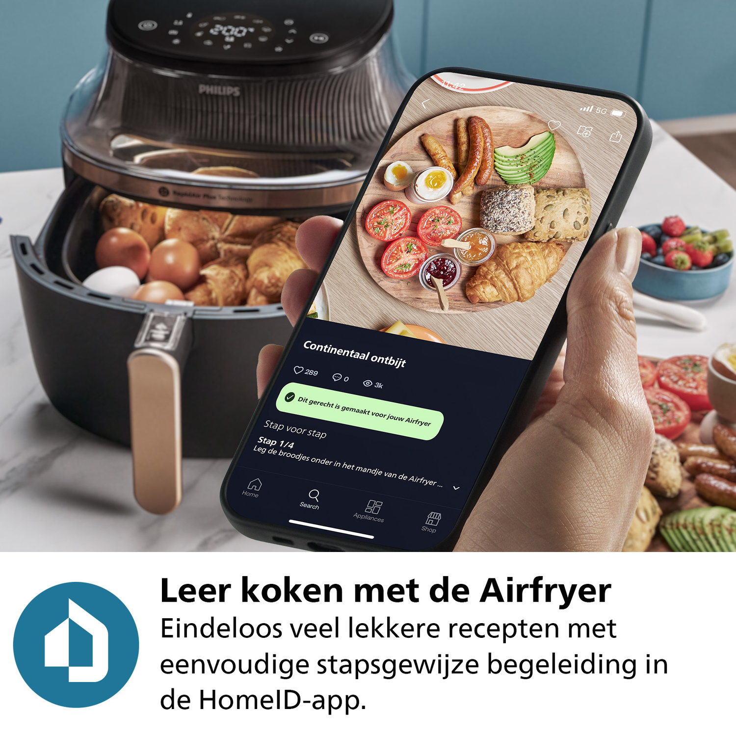 A person holding a phone displaying a recipe app with an air fryer and food on a table.