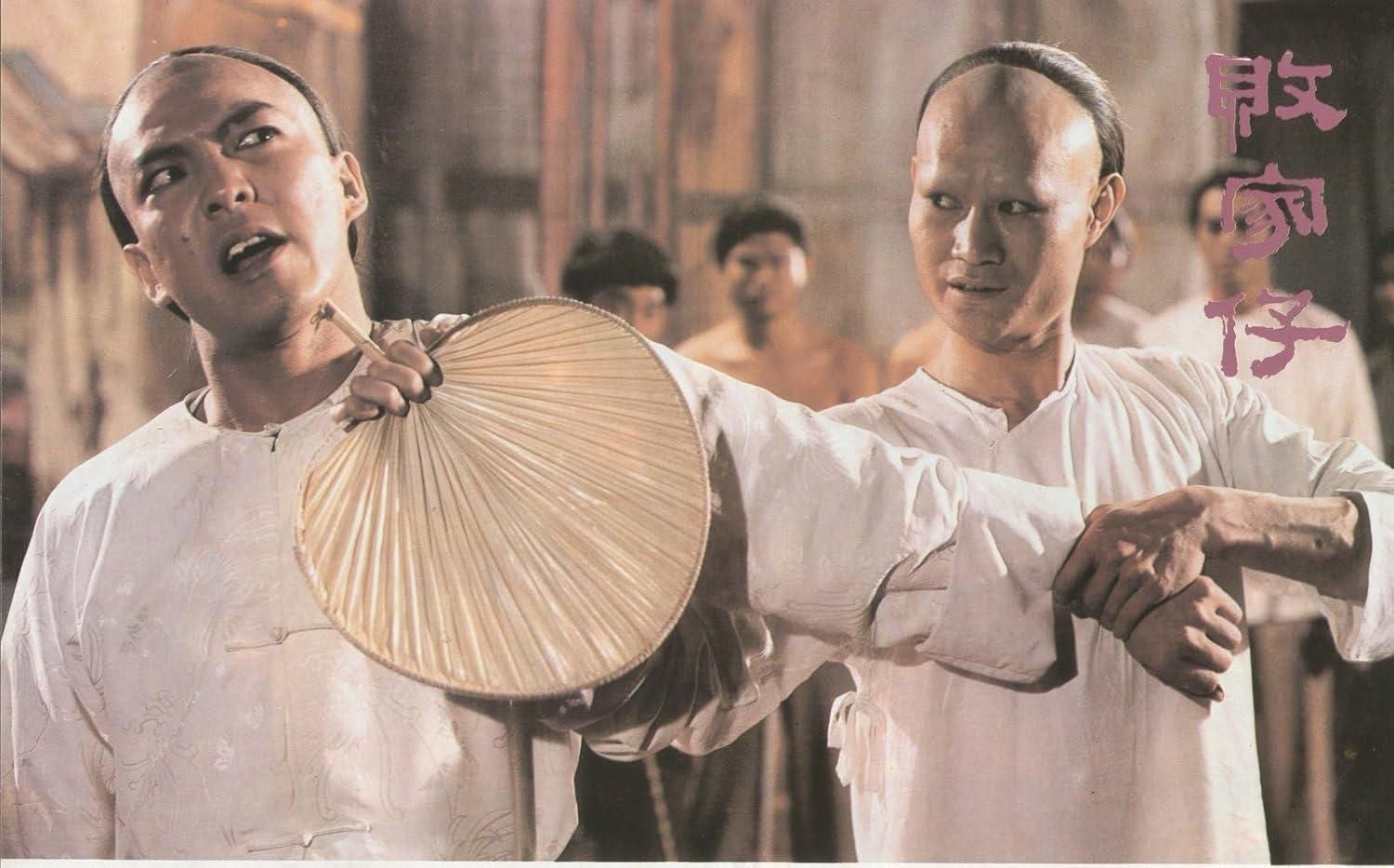 Zwei Männer in traditioneller chinesischer Kleidung, einer mit Fächer, der andere mit Hals.