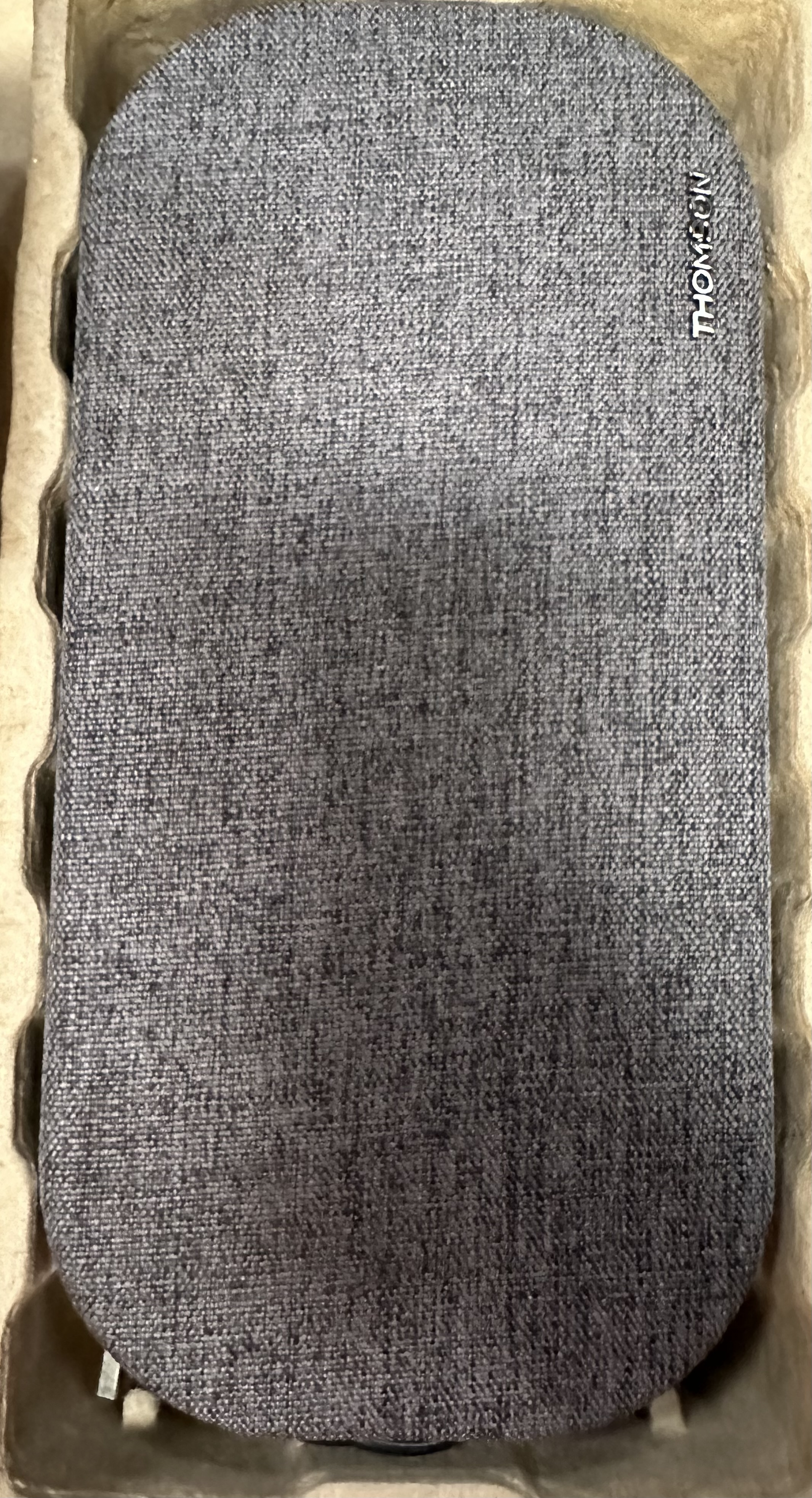 Szary głośnik z tkaniny z logo Thomson w kartonowym pudełku.