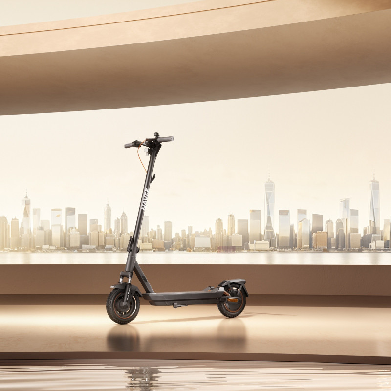 Czarny skuter elektryczny Juvee na tle miasta z nowoczesną panoramą.