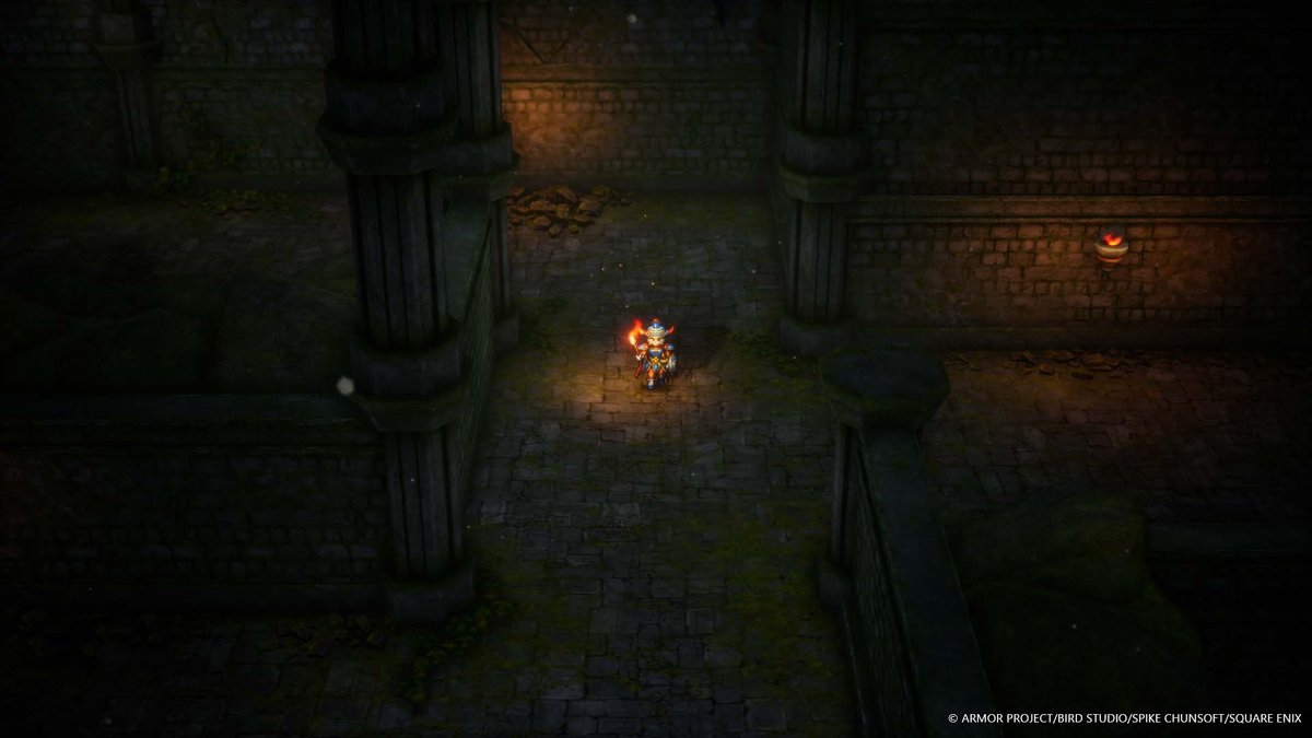 Une scène de jeu vidéo. Un personnage avec une épée se tient dans un couloir de pierre.