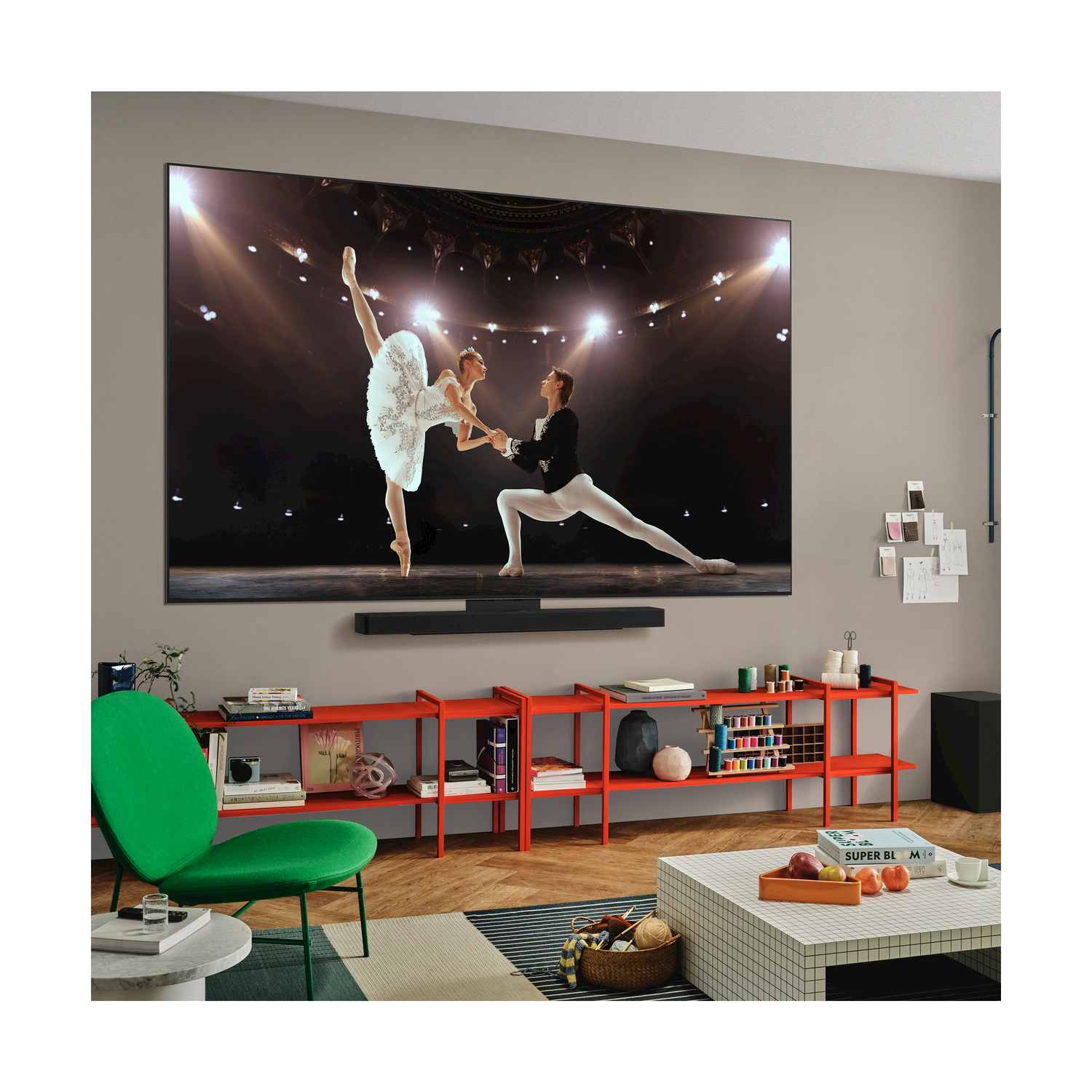 Una grande TV che mostra un'esibizione di balletto. Una soundbar e mensole rosse vicine.