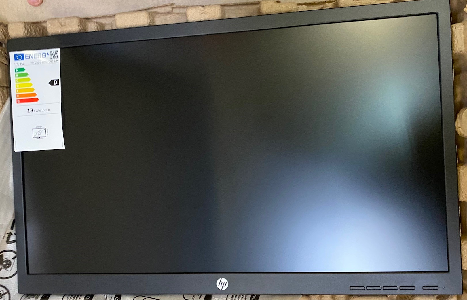 Monitor HP, w opakowaniu, wyświetla czarny ekran z etykietą energetyczną.