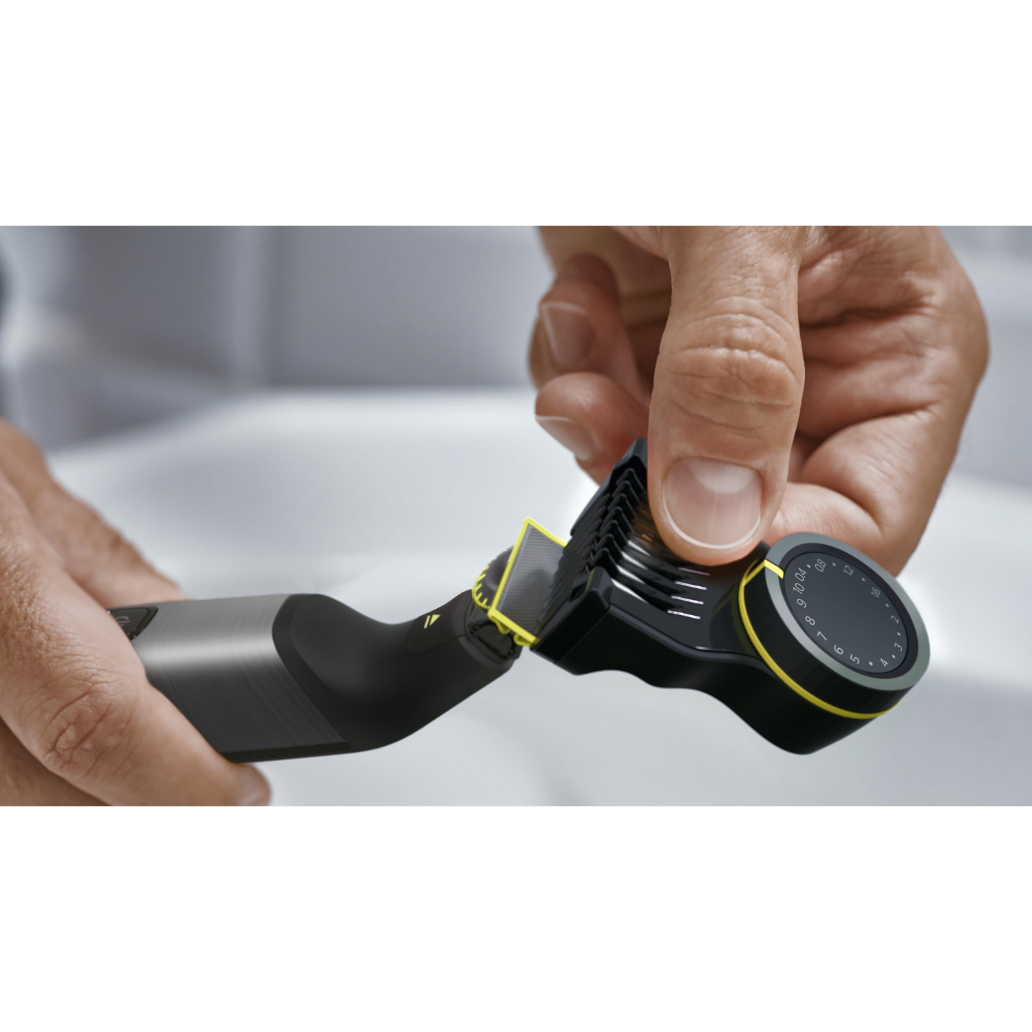 Close-up of hand adjusting a trimmer's comb attachment. It is gray and black.