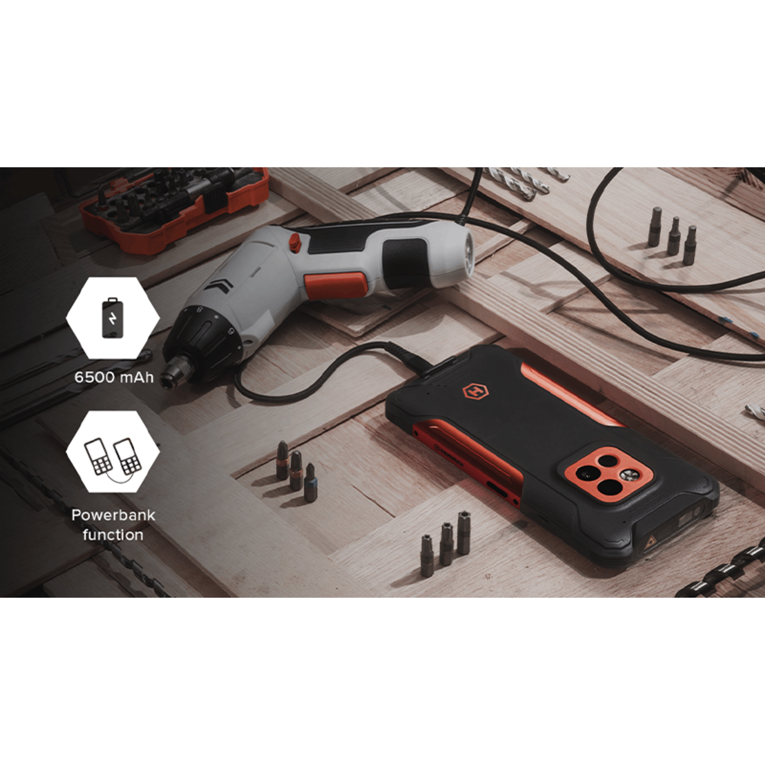 Elektrische schroevendraaier en telefoon opladen. Zwarte en oranje telefoonhoes. Houten achtergrond met gereedschap.