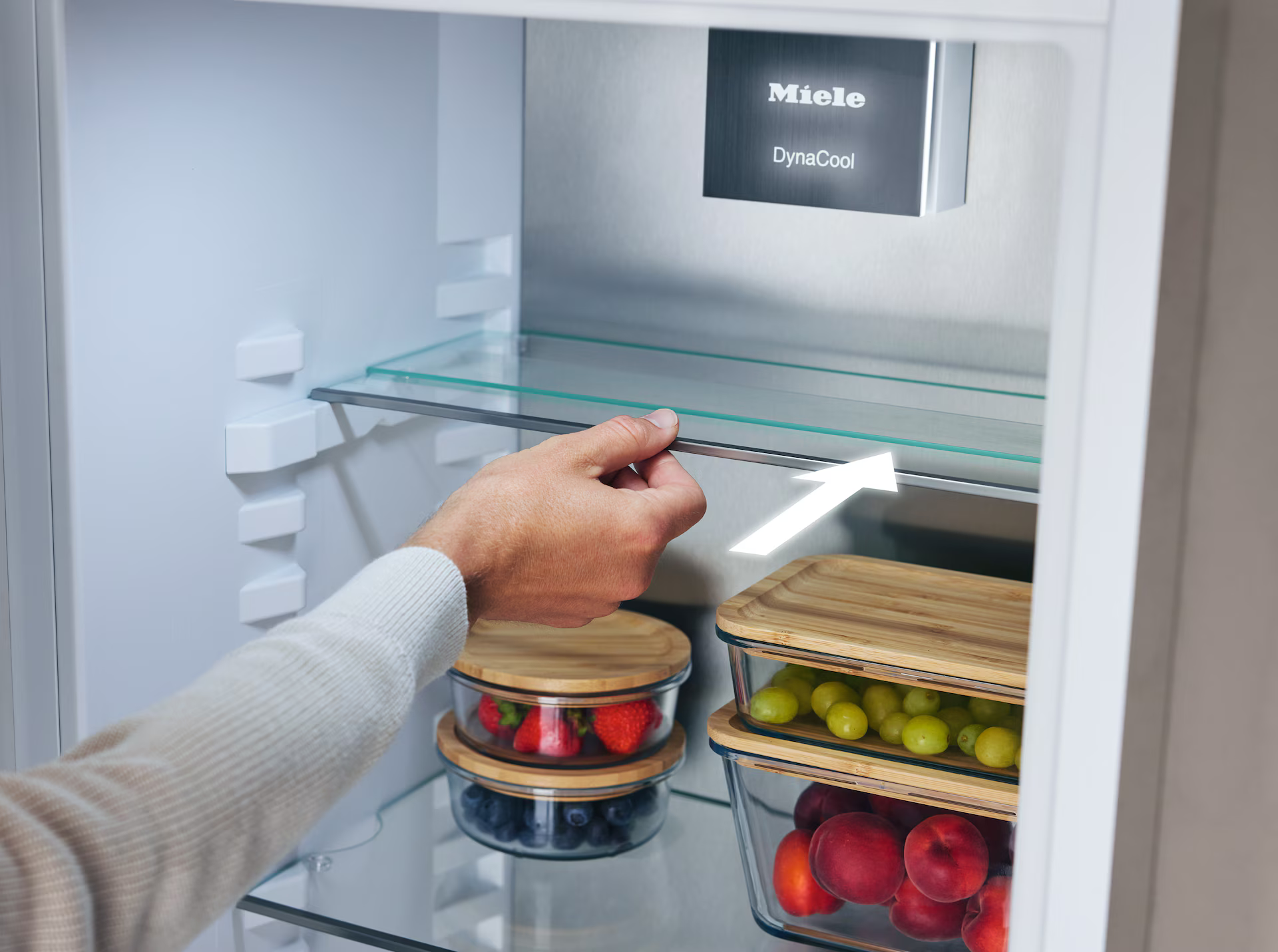 Hand entfernt Glasregal aus Kühlschrank. Früchte im Kühlschrank.